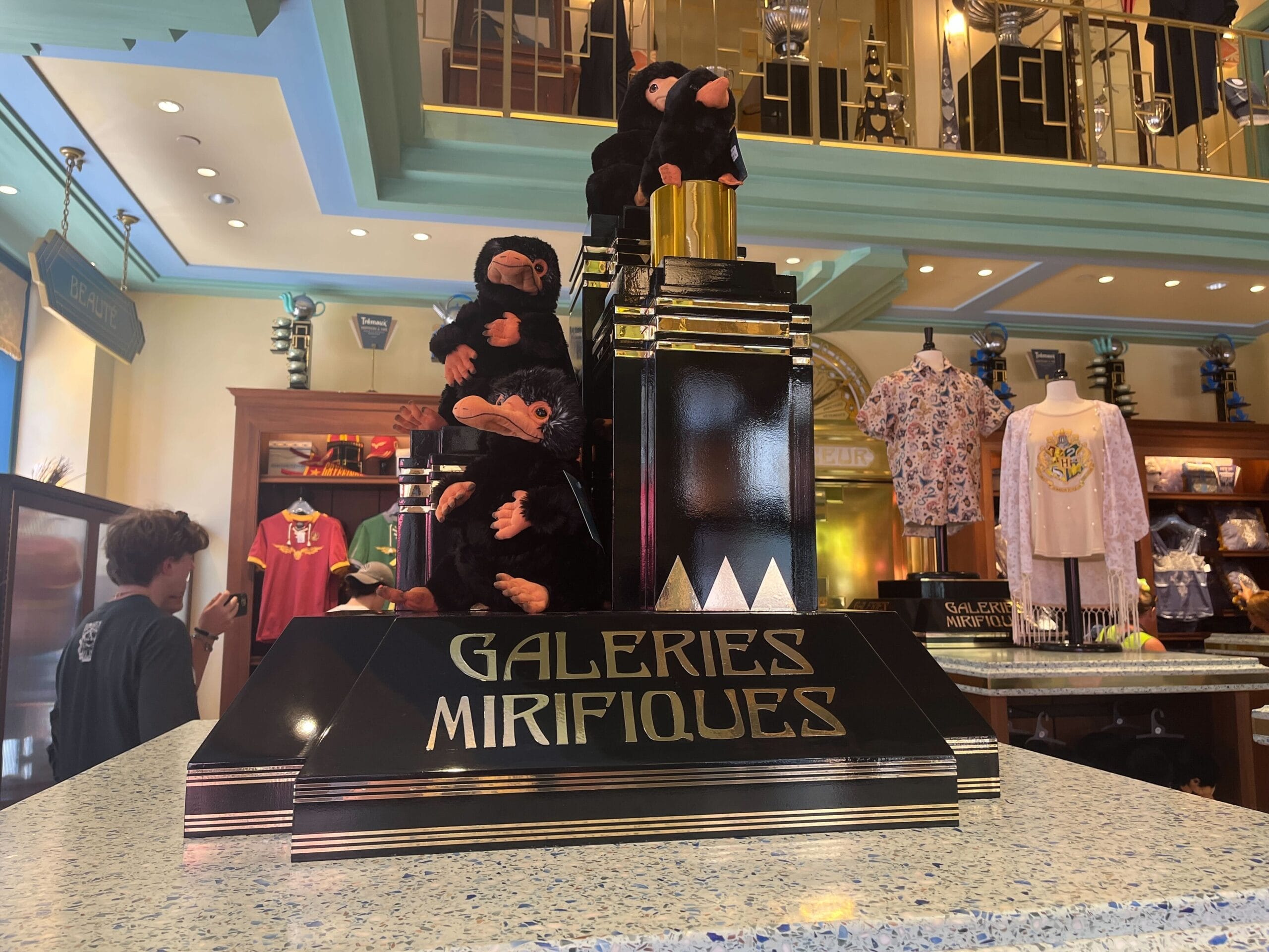 A display with plush Nifflers and a sign reading "Les Galeries Mirifiques" in a themed gift shop.