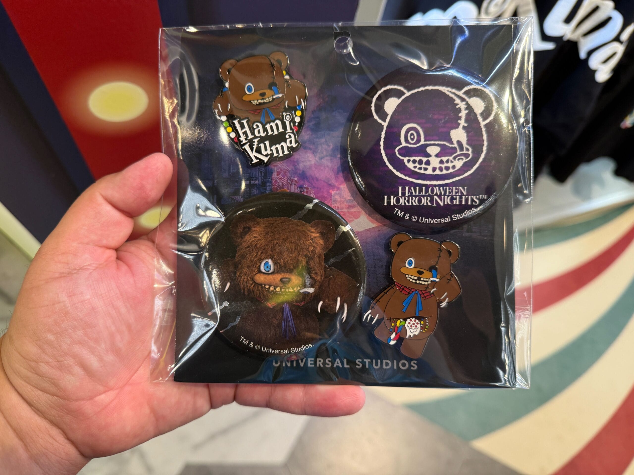 Hand holds a set of four Halloween-themed bear pins from Universal Studios, including "Hamu Kyun!" and Horror Nights designs.