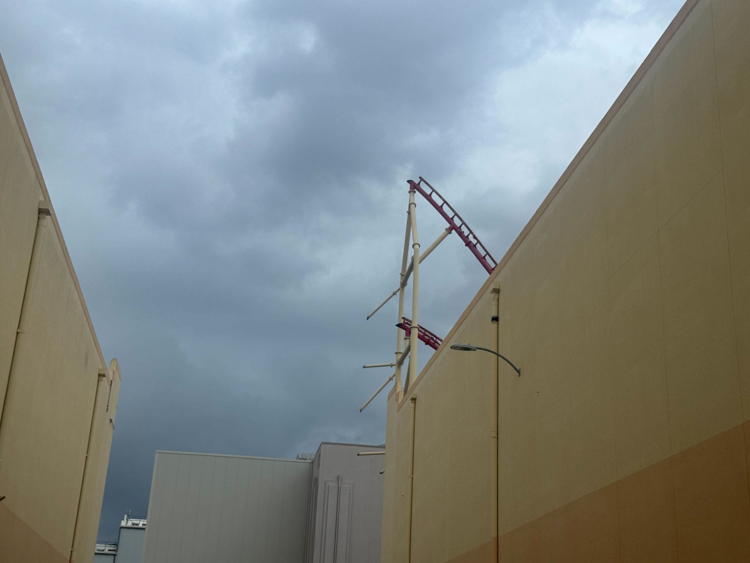 The Rip Ride Rockit roller coaster track peeks above beige buildings at Universal Studios Florida under an overcast sky.