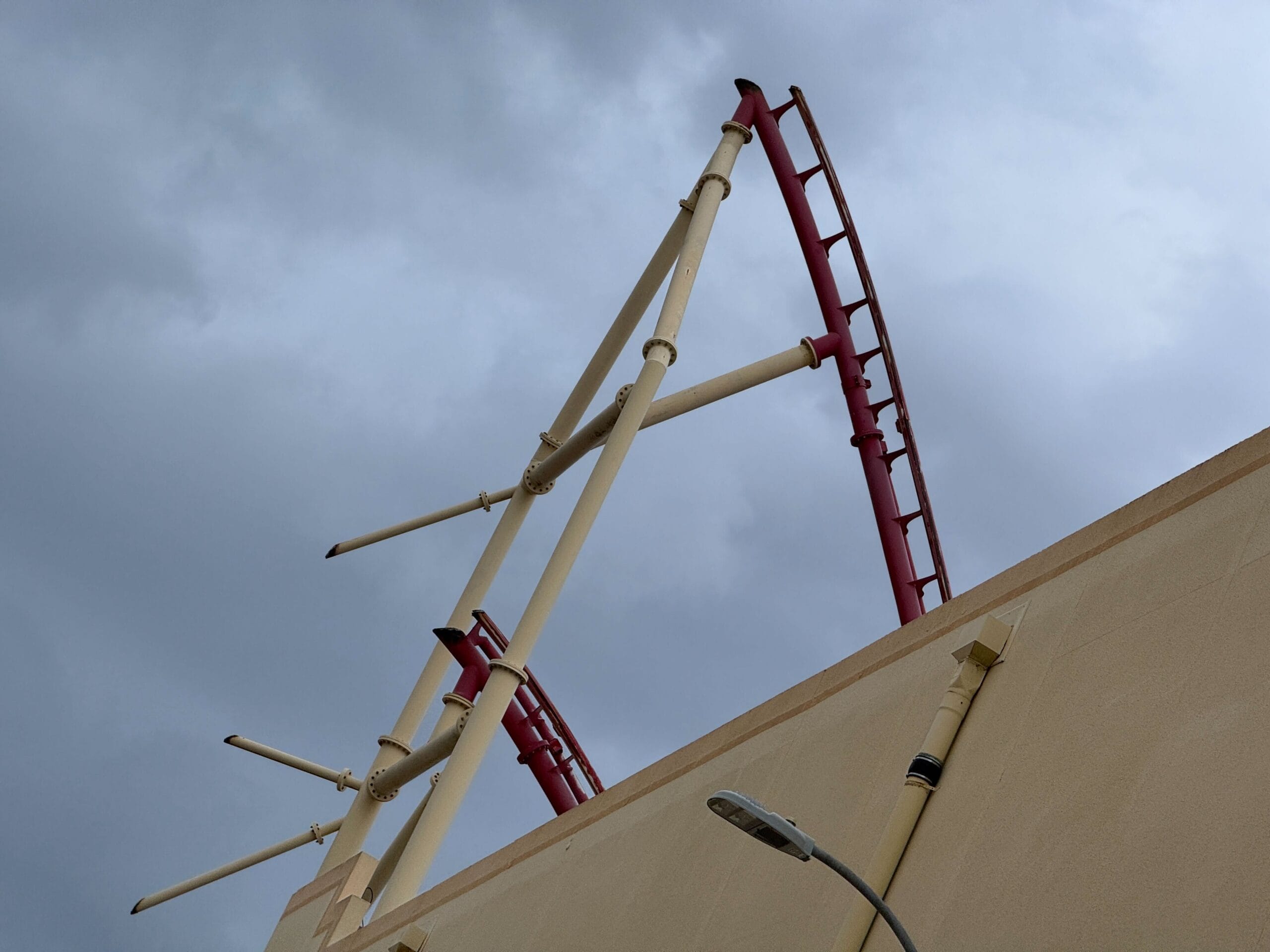The Rip Ride Rockit coaster juts upward behind a tan building at Universal Studios Florida against a cloudy gray sky.