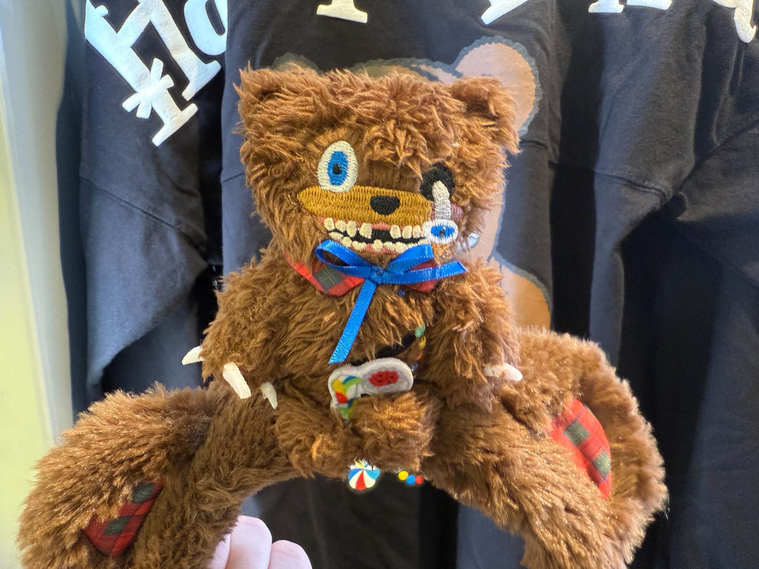A brown HamiKuma Merchandise plush bear headband with stitched blue eyes, scary teeth, and candy decorations.