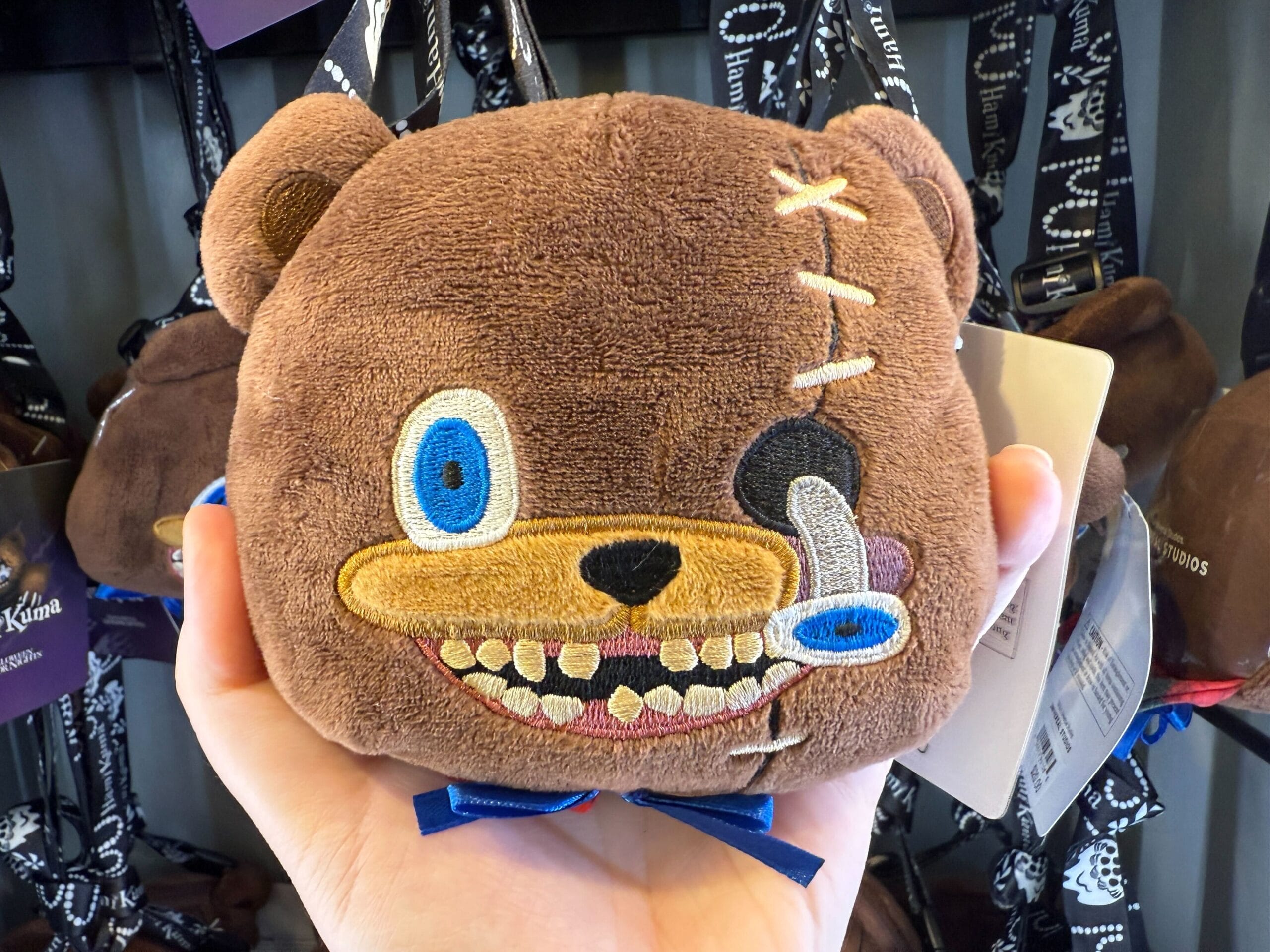 A hand holds a quirky, spooky HamiKuma Merchandise bear purse at Universal Orlando Resort during Halloween Horror Nights 2025.