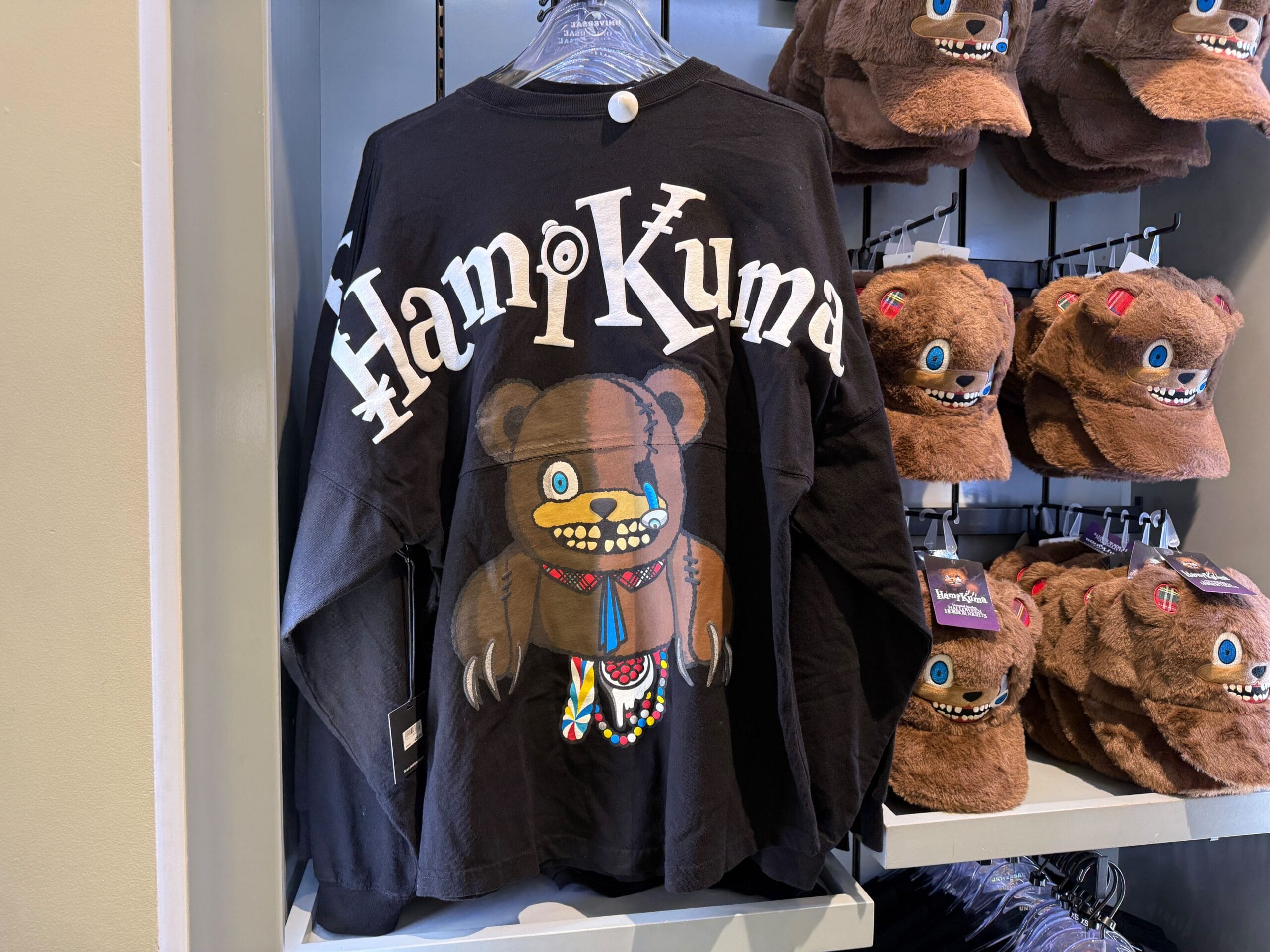 Black long-sleeve shirt with "HamuKuma" text and a cartoon bear, part of HamiKuma Merchandise at Universal Orlando Resort.