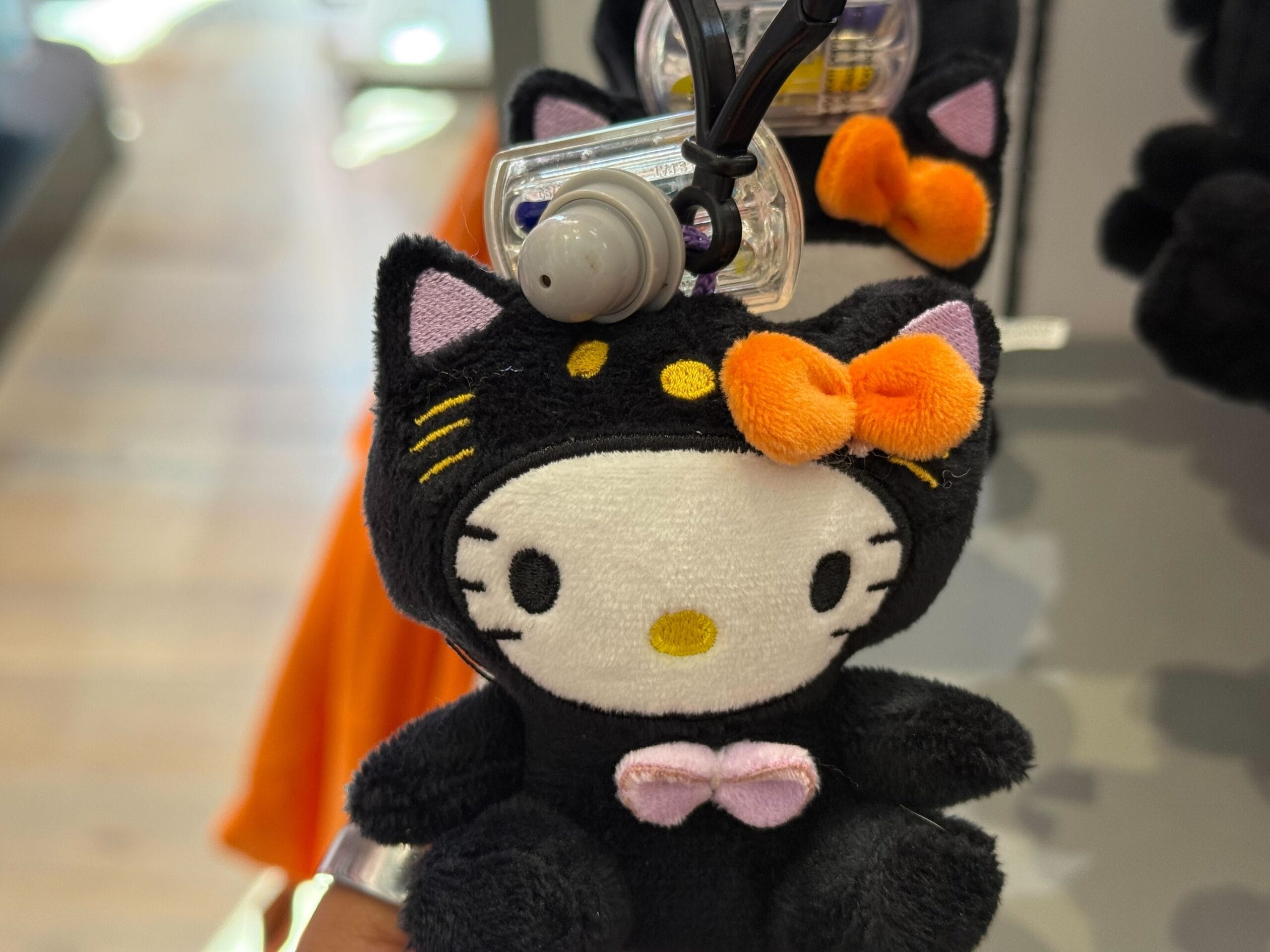 Plush Hello Kitty in a black cat costume with orange bow—cute Halloween merchandise at Universal Studios Hollywood.