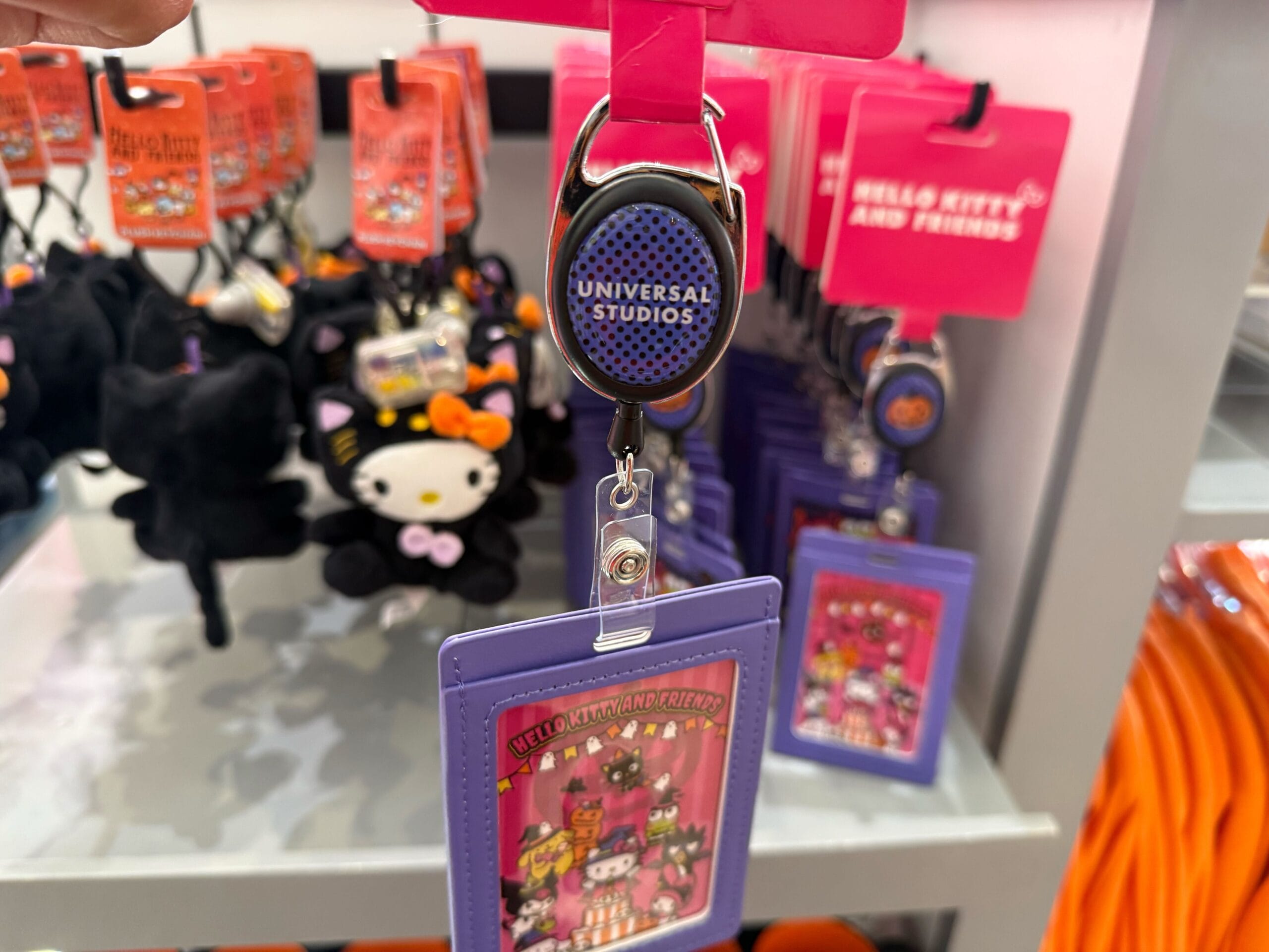 A Universal Studios Hollywood badge holder featuring a purple Hello Kitty and Friends card on a store display.