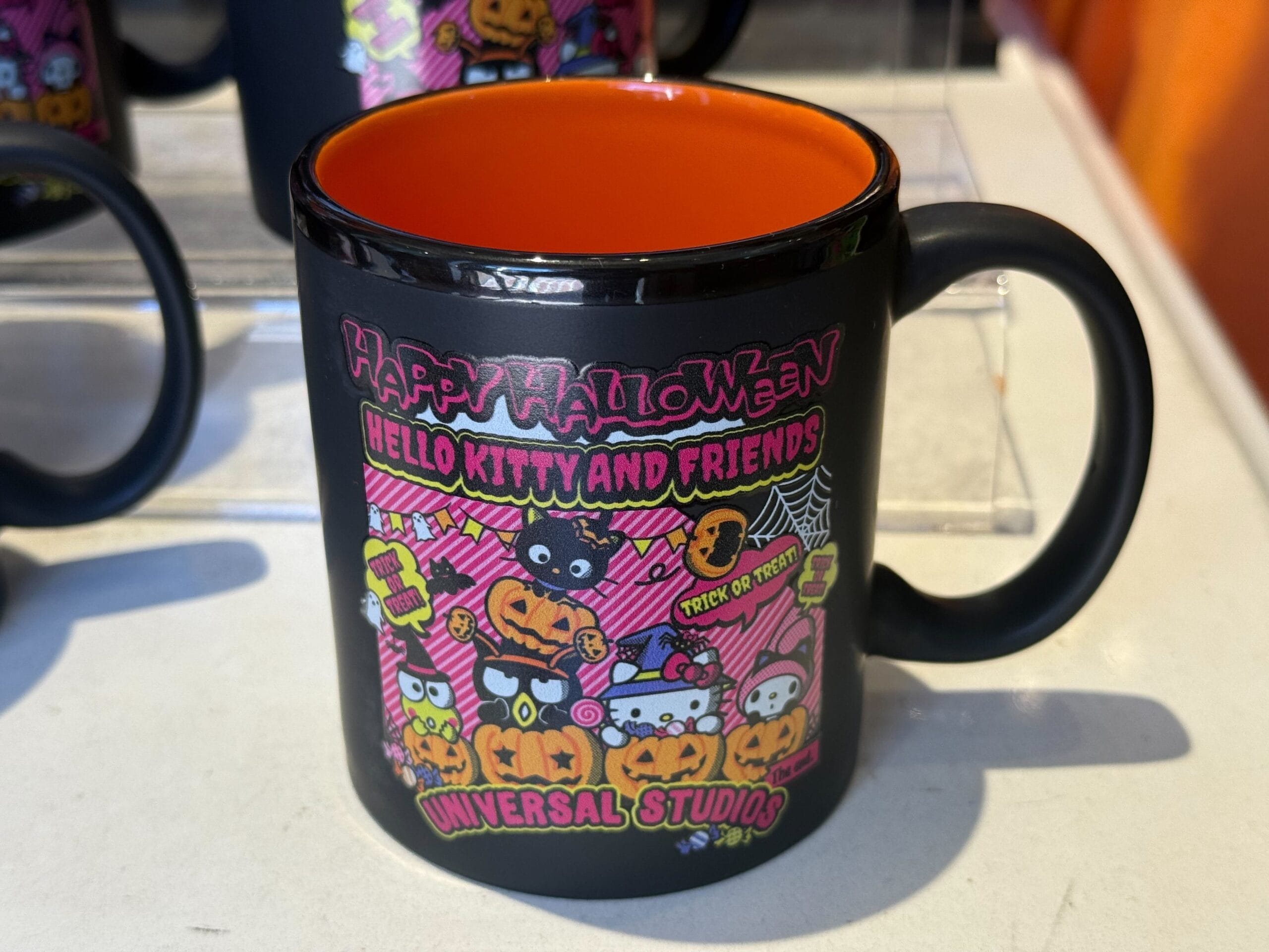 Hello Kitty Halloween Merchandise Black mug with orange interior features Hello Kitty Halloween design and "Universal Studios Hollywood" text.