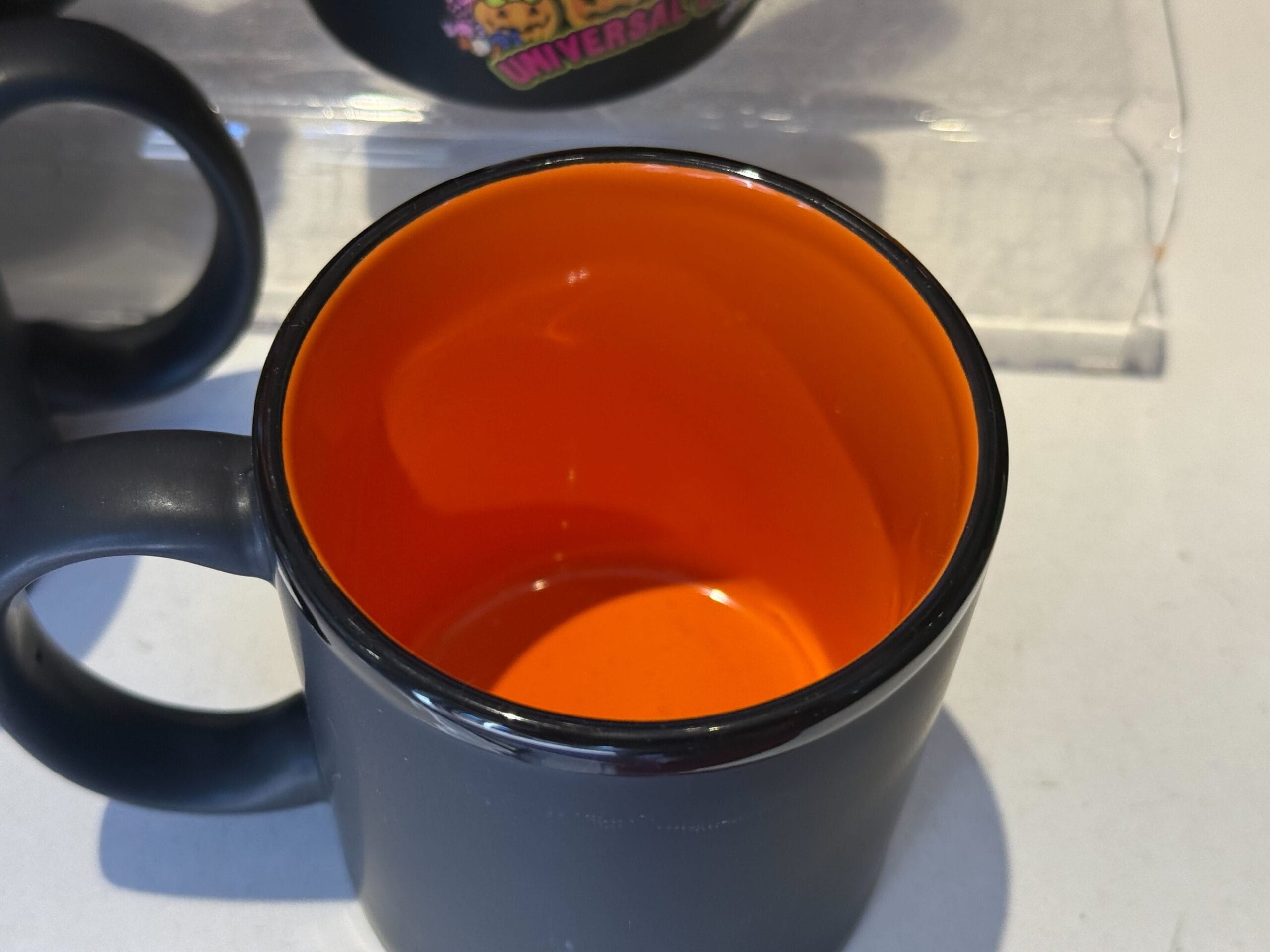 Black mug with bright orange interior, perfect for Universal Studios Hollywood Halloween merchandise collectors.