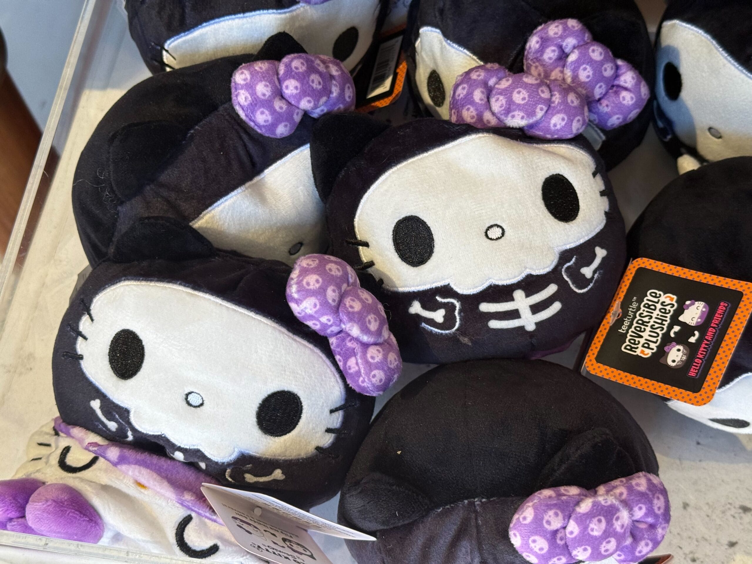 Plush Hello Kitty dolls with skeleton designs and purple bows, perfect as Halloween merchandise at Universal Studios Hollywood.
