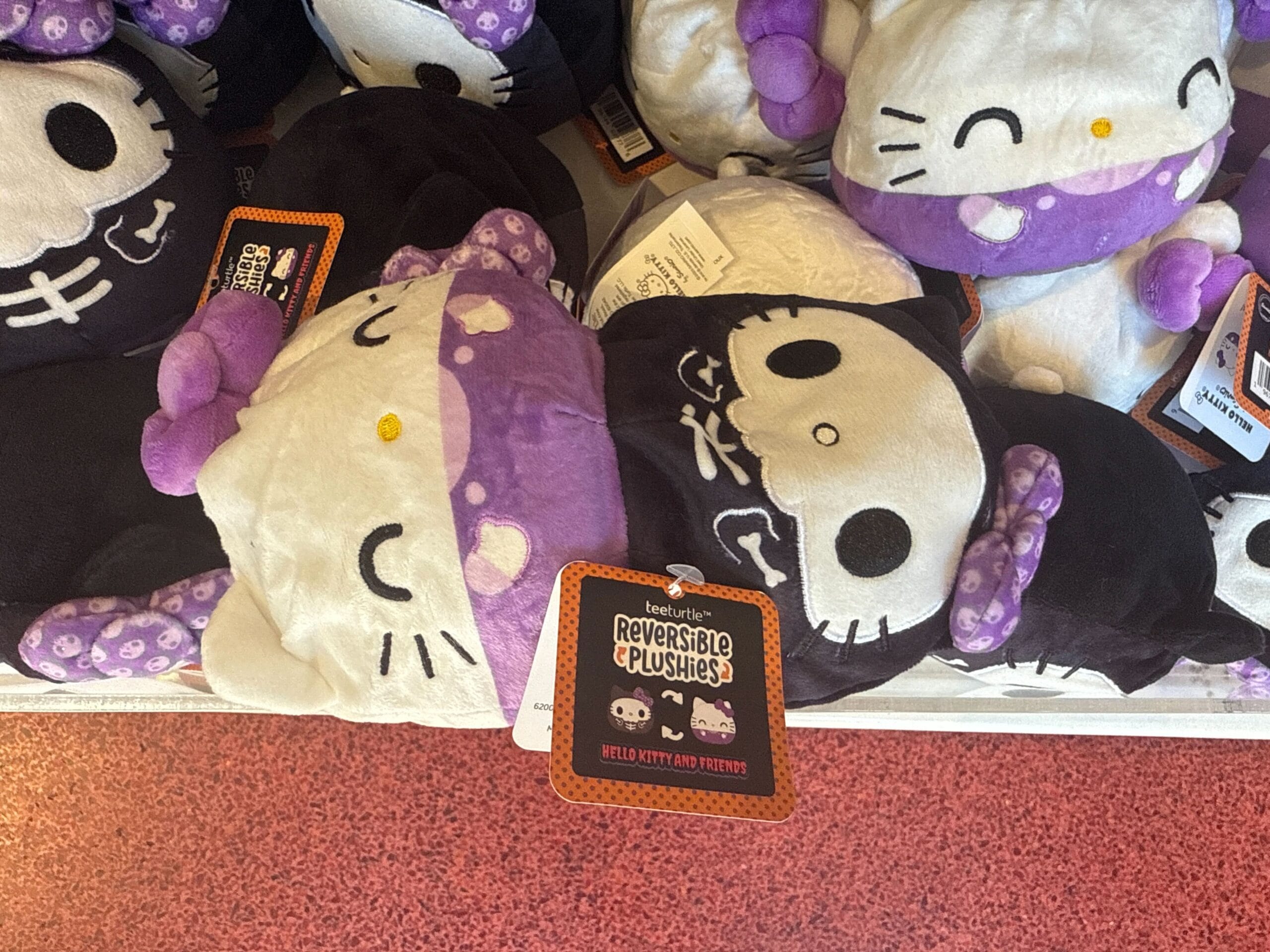 Reversible Hello Kitty Halloween plushies with skeleton and polka-dot designs, perfect for Hello Kitty merchandise fans.
