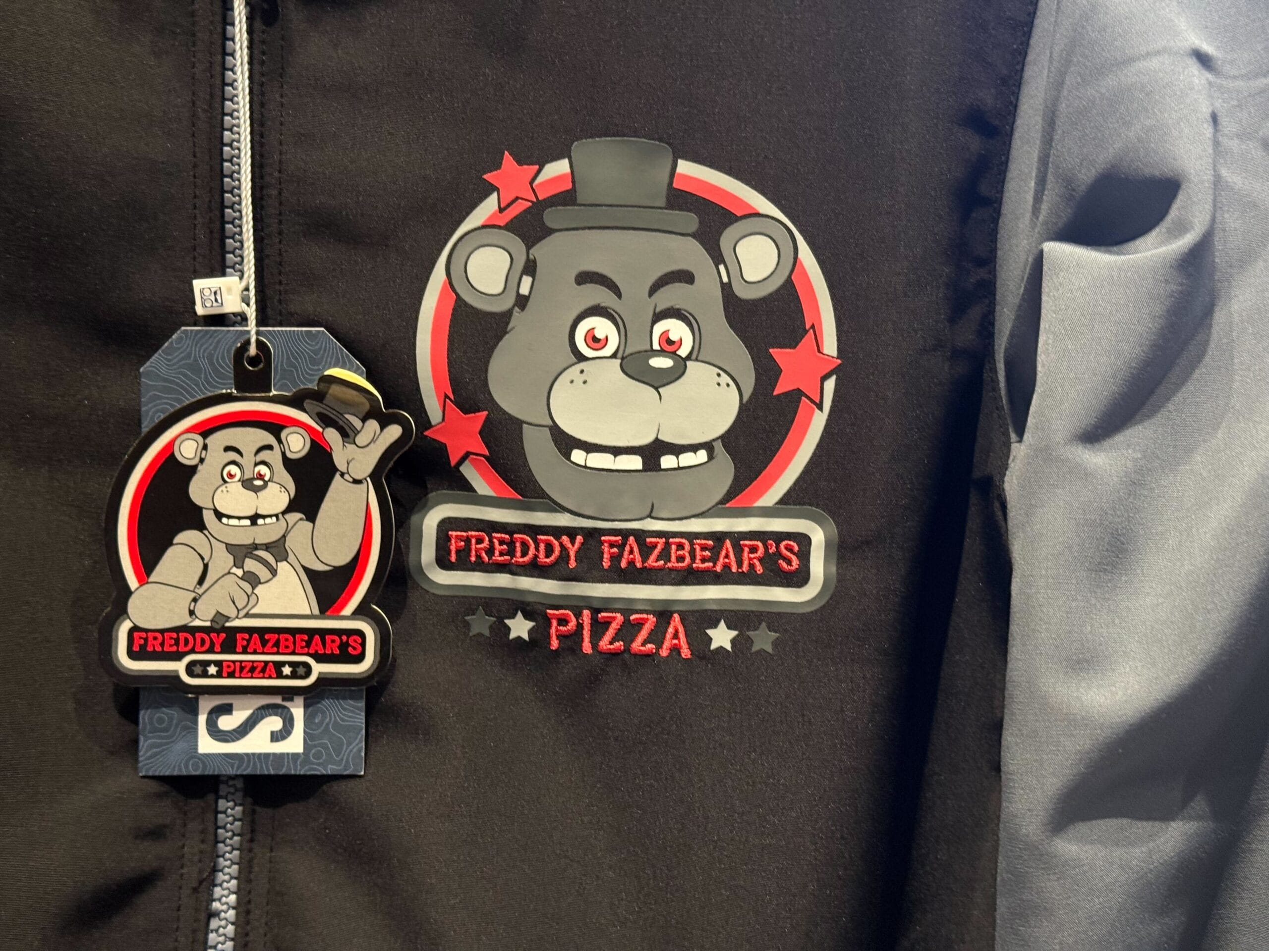 A black jacket with a "Freddy Fazbear's Pizza" logo, part of the HHN Merch 2025 at Universal Studios Hollywood.