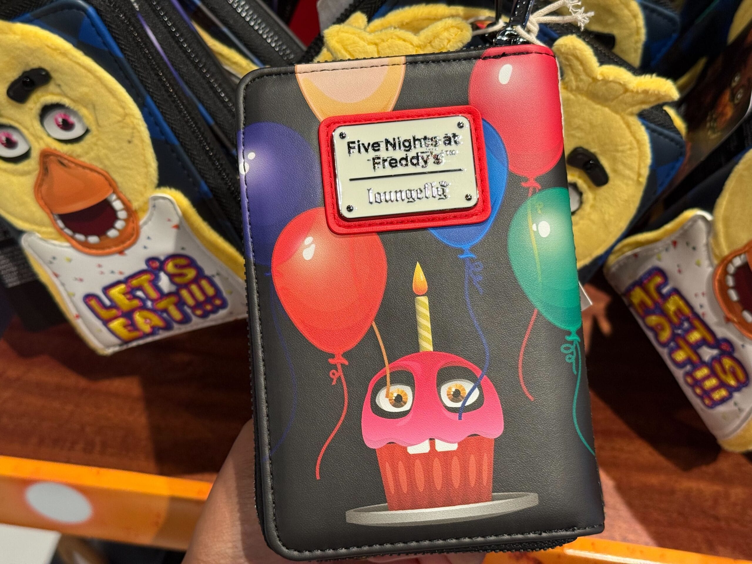 A wallet with a Five Nights at Freddy's cupcake, balloons, and candle—perfect for Halloween Horror Nights Merchandise fans.
