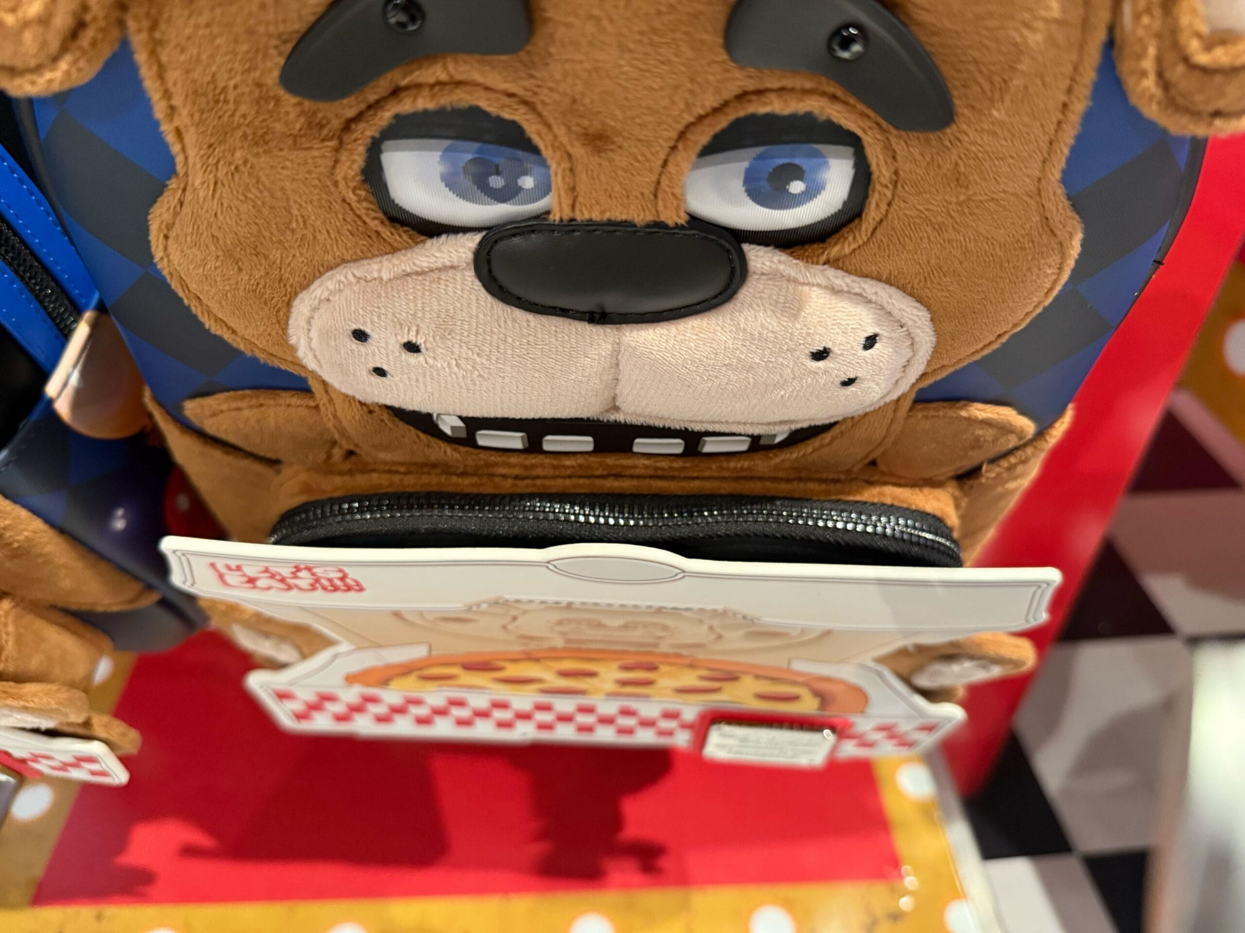 A plush bear face backpack with a pizza tag, part of the HHN Merch 2025 at Universal Studios Hollywood.