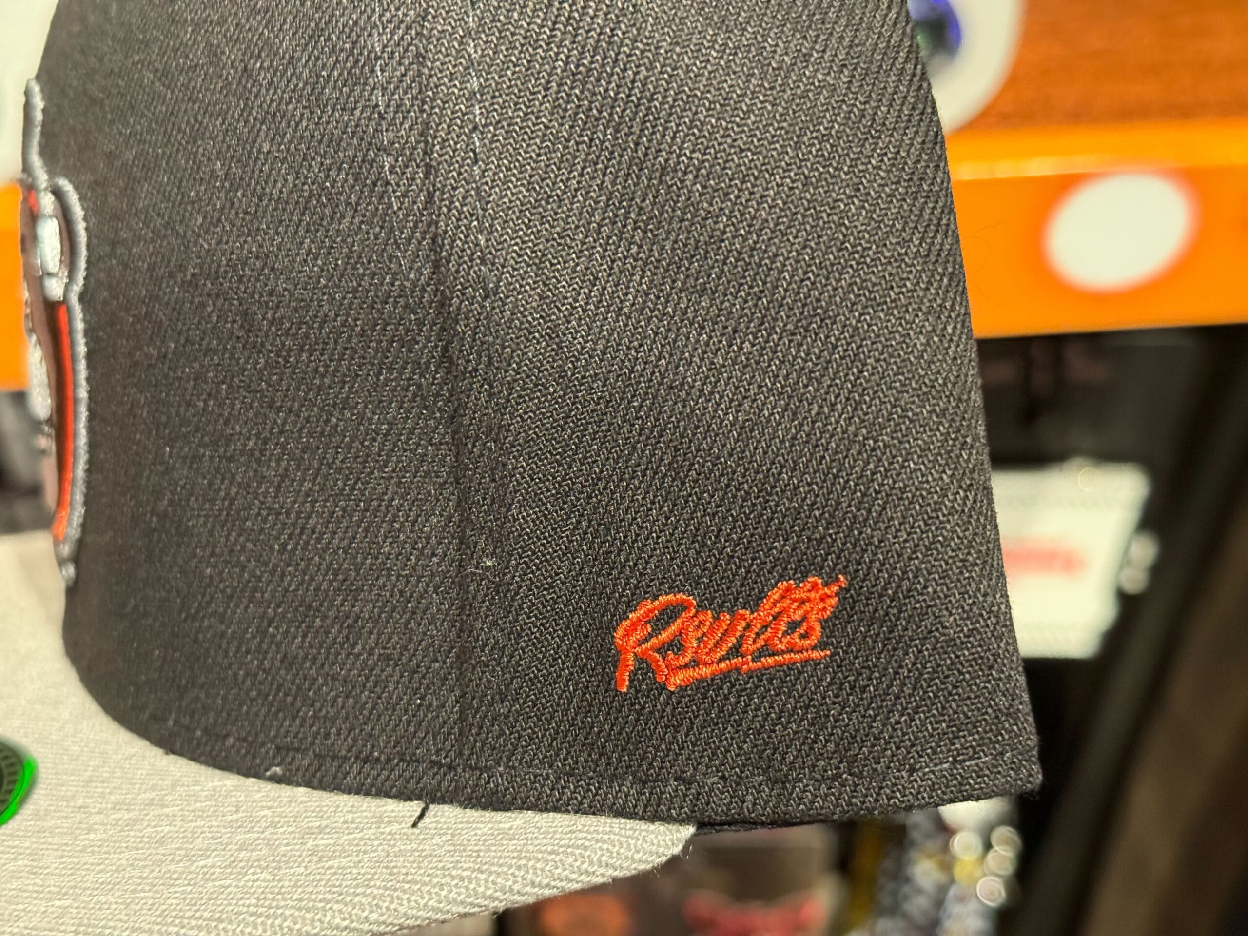 Close-up of a black and gray cap with "Roots" embroidered in red, part of Halloween Horror Nights Merchandise.