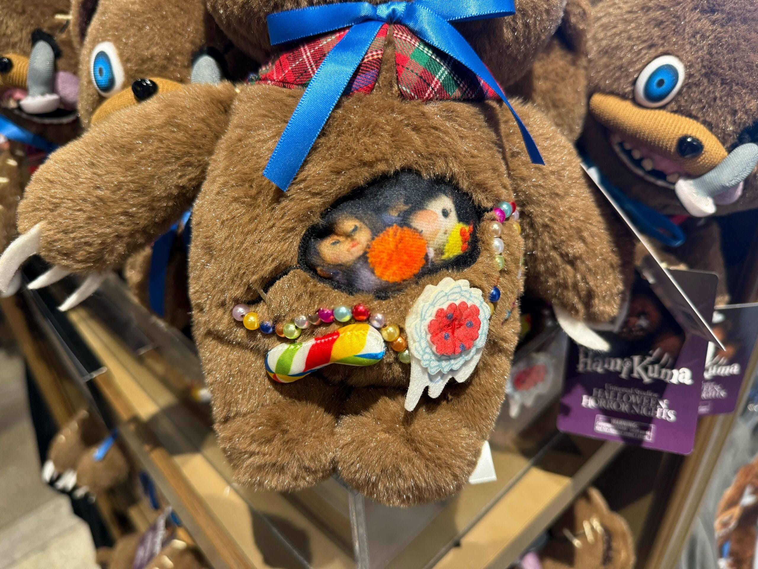 Close-up of a plush bear with a pouch showing three small animals, part of Universal Studios Hollywood Halloween Horror Nights Merchandise.