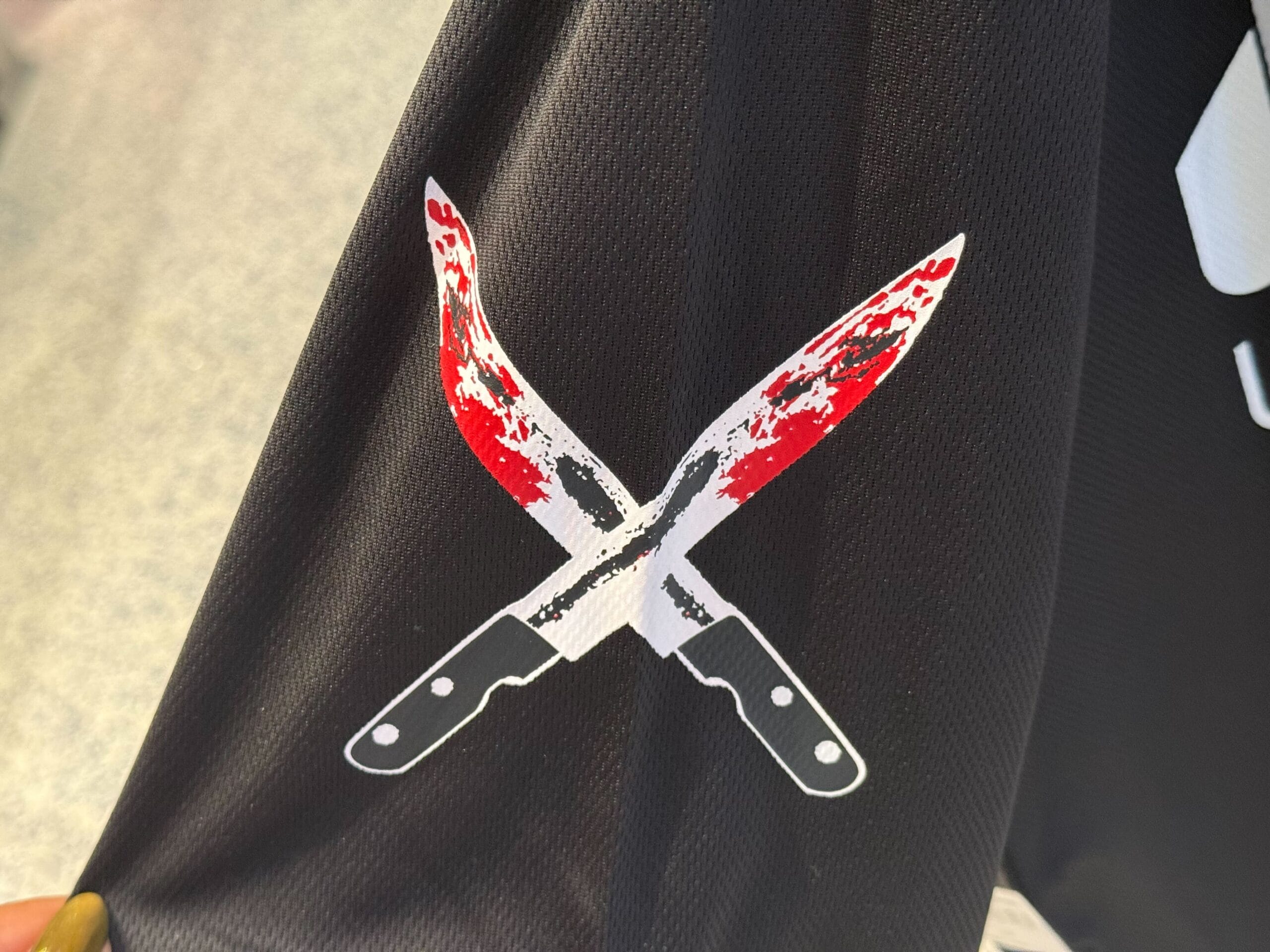 Two bloody kitchen knives cross on black fabric—a must-have for Halloween Horror Nights Merchandise collectors.