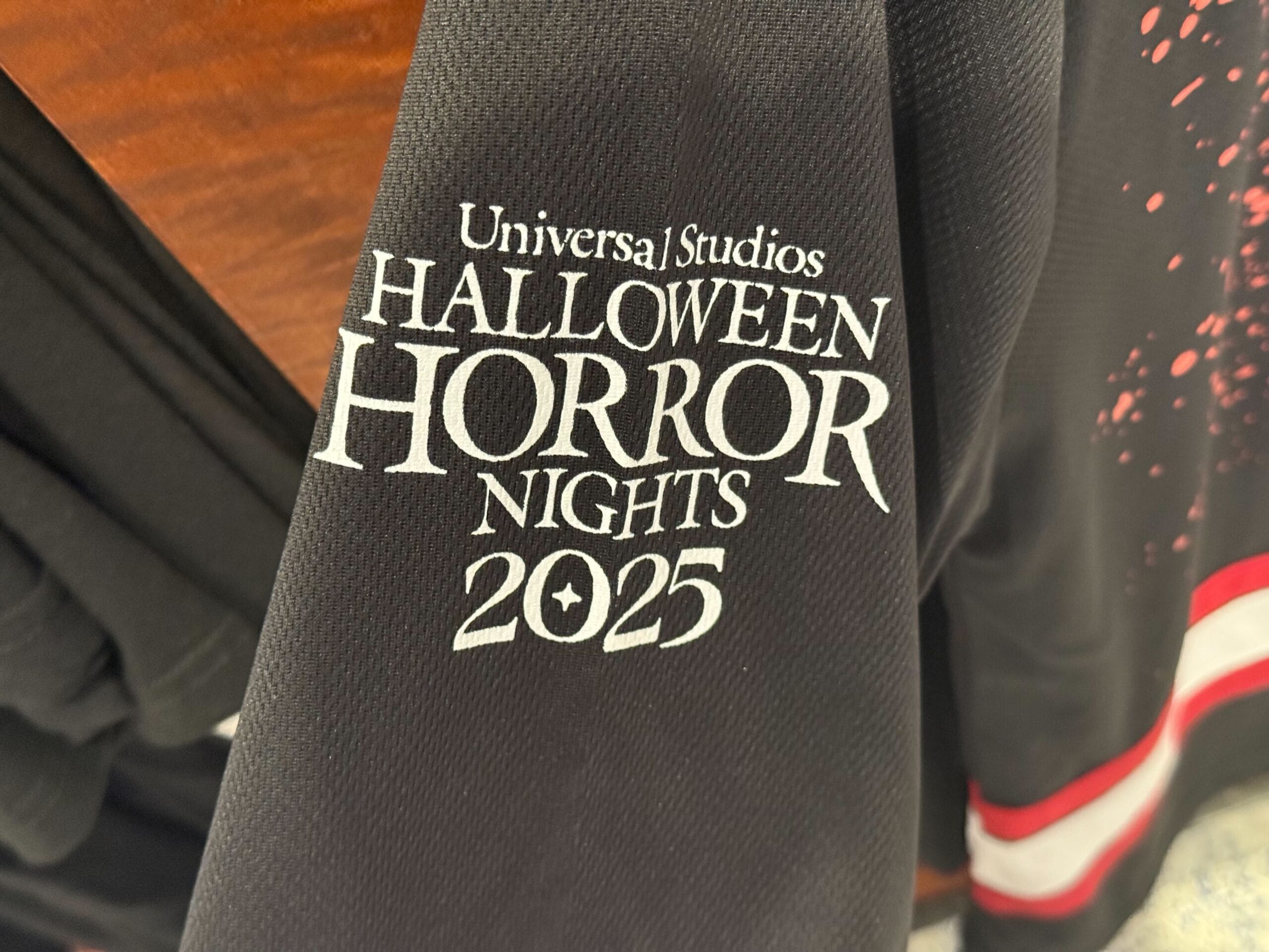 Close-up of a black sleeve with "Halloween Horror Nights 2025" logo—exclusive HHN Merch 2025 from Universal Studios Hollywood.