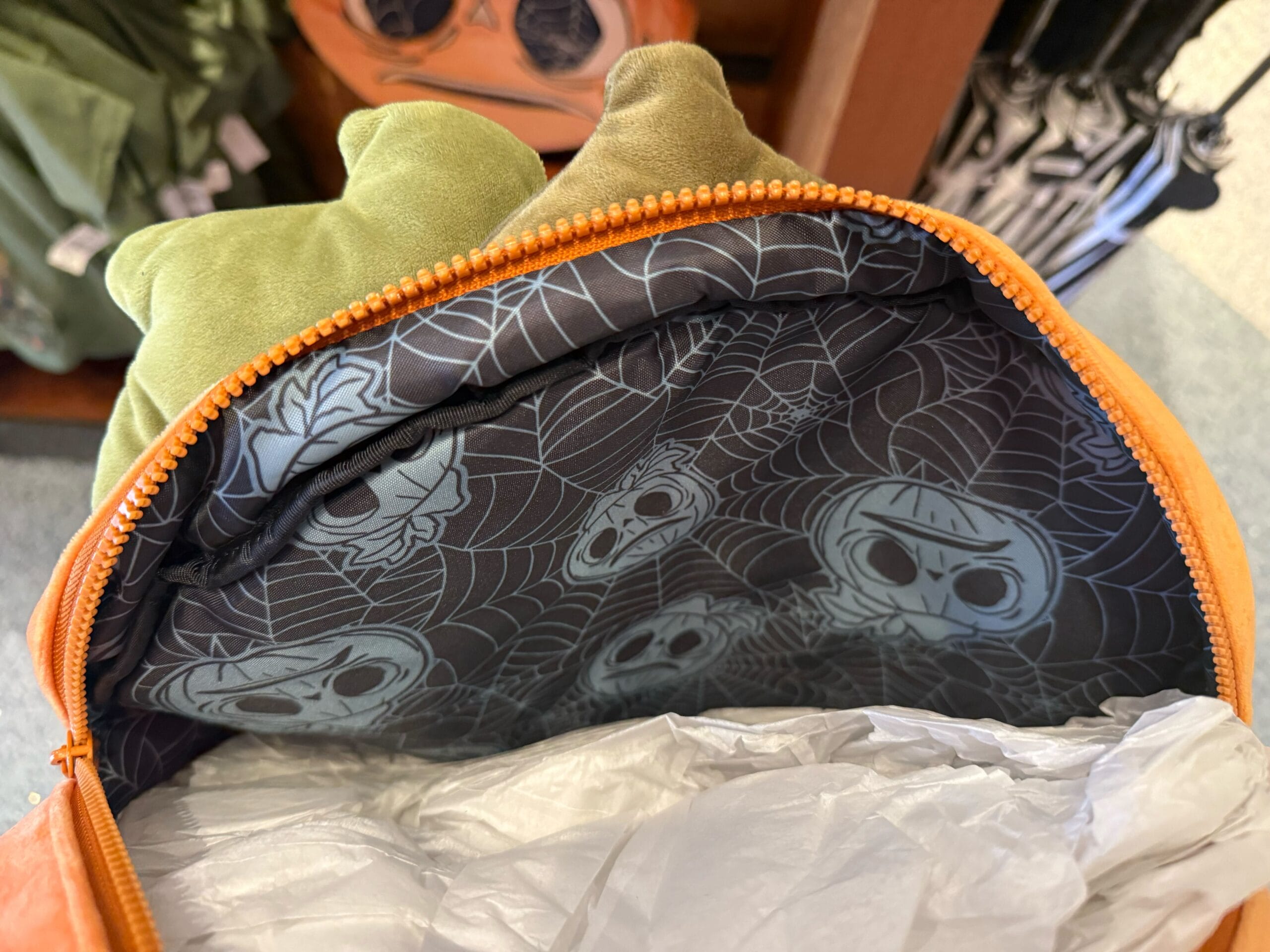 Open orange backpack with green top, lined with cartoon skulls—perfect HHN Merch 2025 at Universal Studios Hollywood.