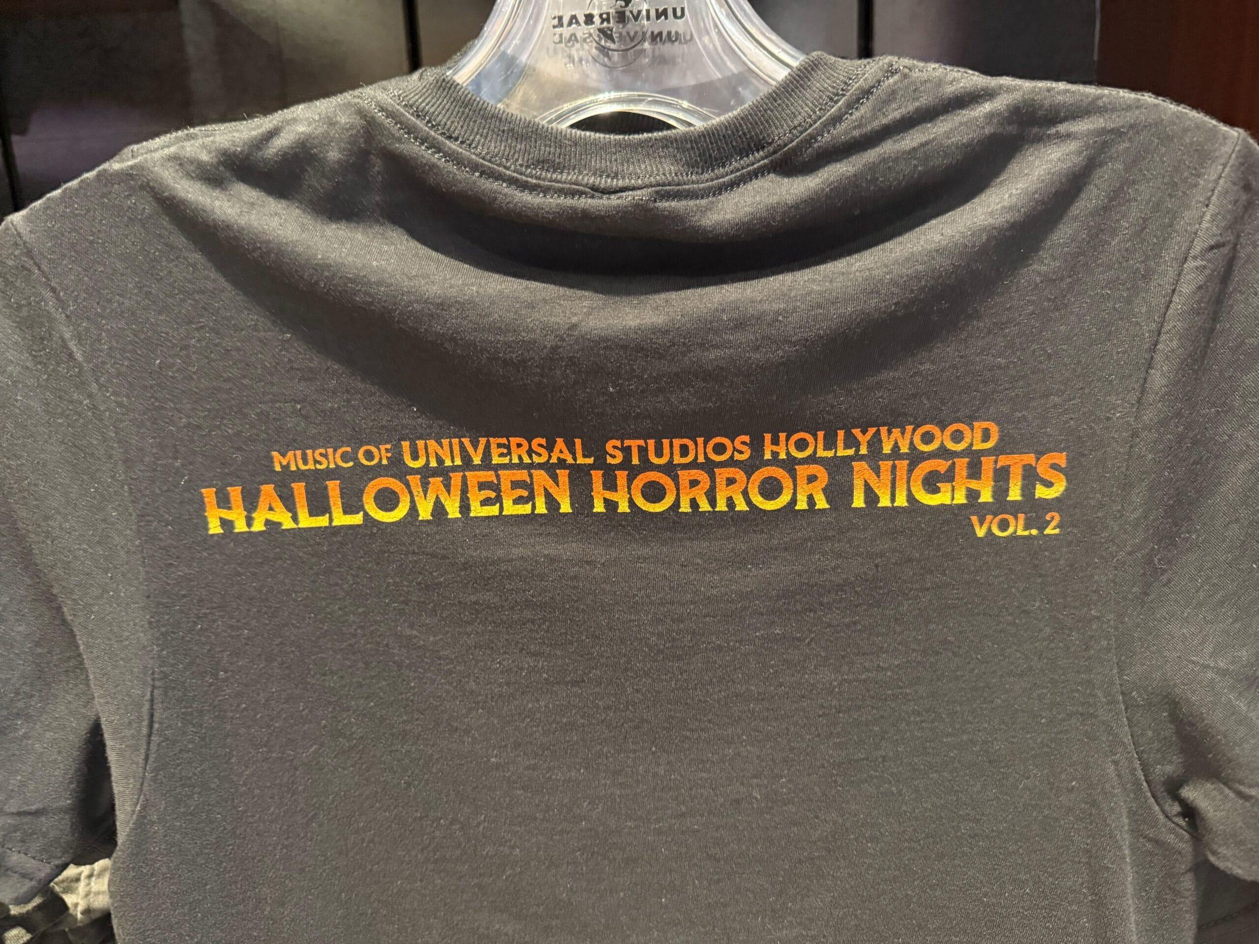 Black T-shirt with orange text: "Halloween Horror Nights Vol. 2, Music of Universal Studios Hollywood HHN Merch 2025.