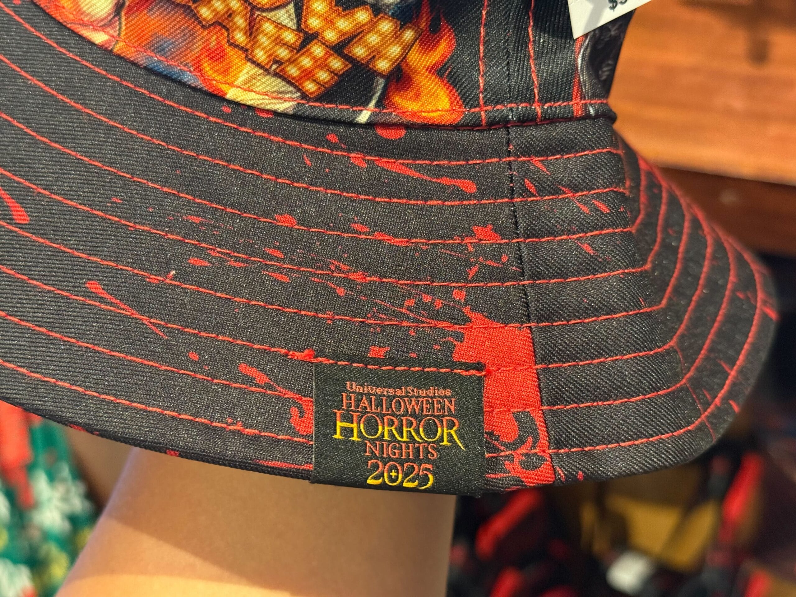 A close-up of a black and red bucket hat, part of the HHN Merch 2025 at Universal Studios Hollywood.