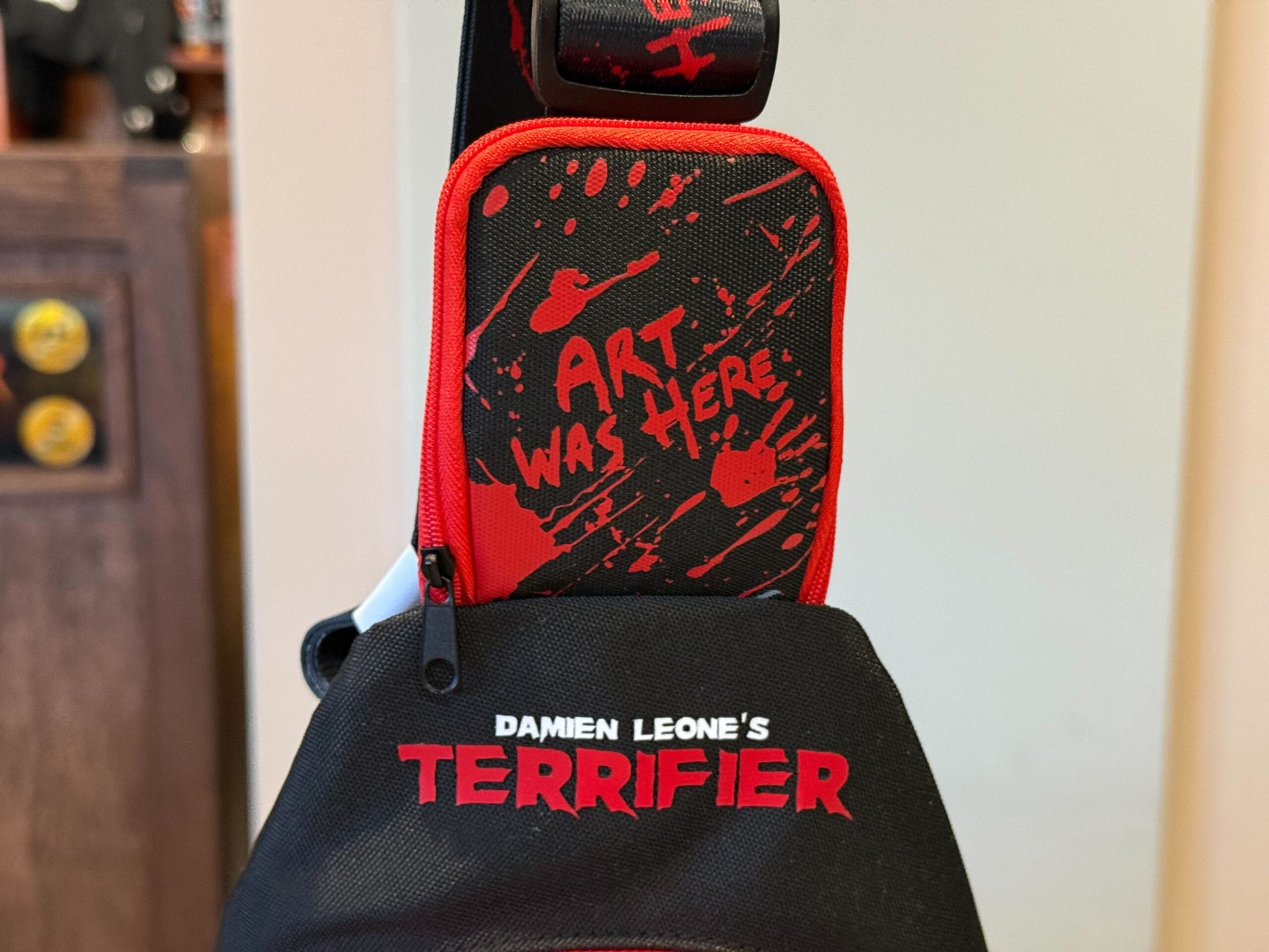 A black-and-red pouch with "ART WAS HERE" and "Damien Leone's TERRIFIER," exclusive HHN Merch 2025.