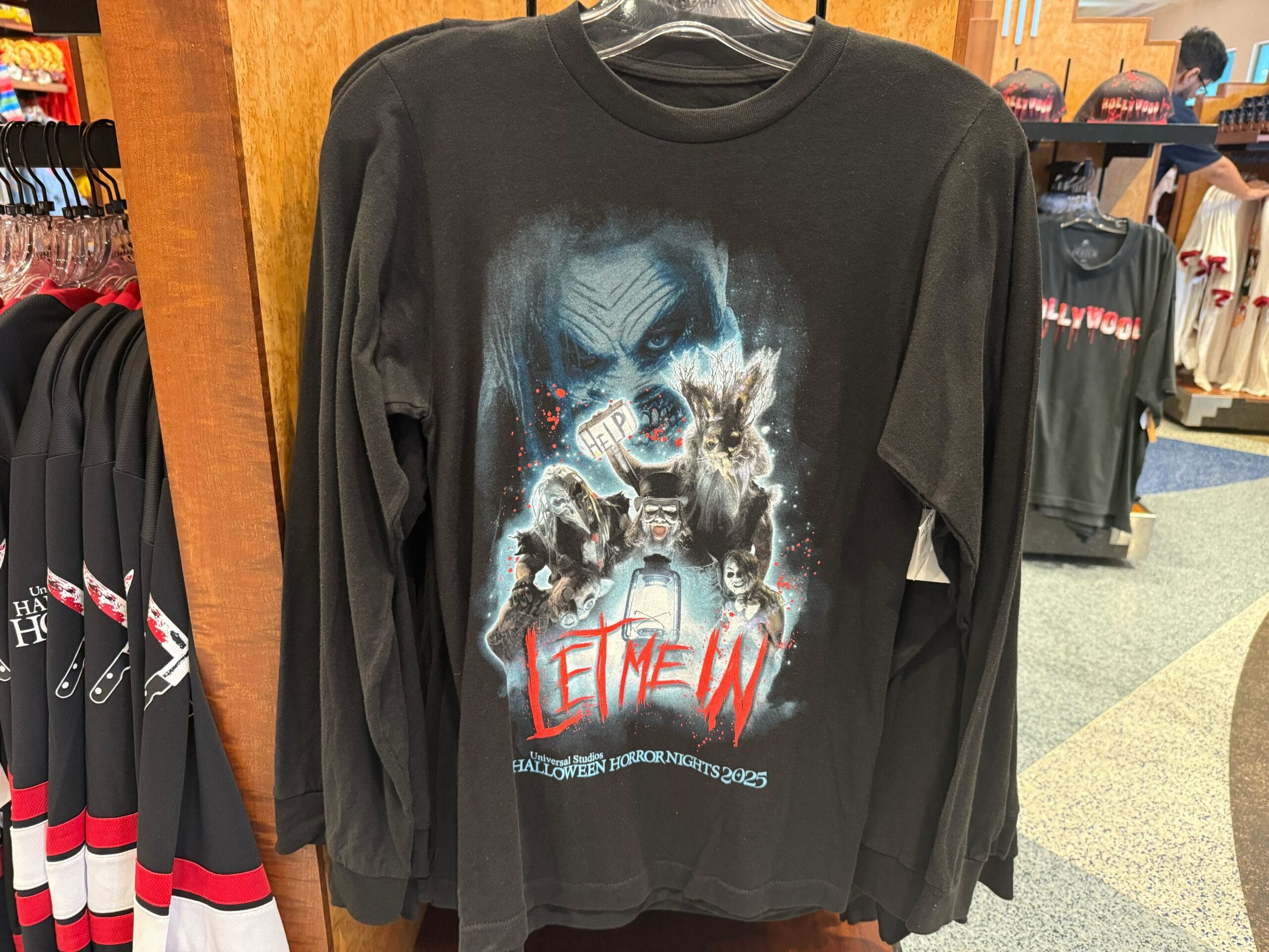 Black long-sleeve shirt with horror illustrations and "LET ME IN" text, perfect HHN Merch 2025 at Universal Studios Hollywood.