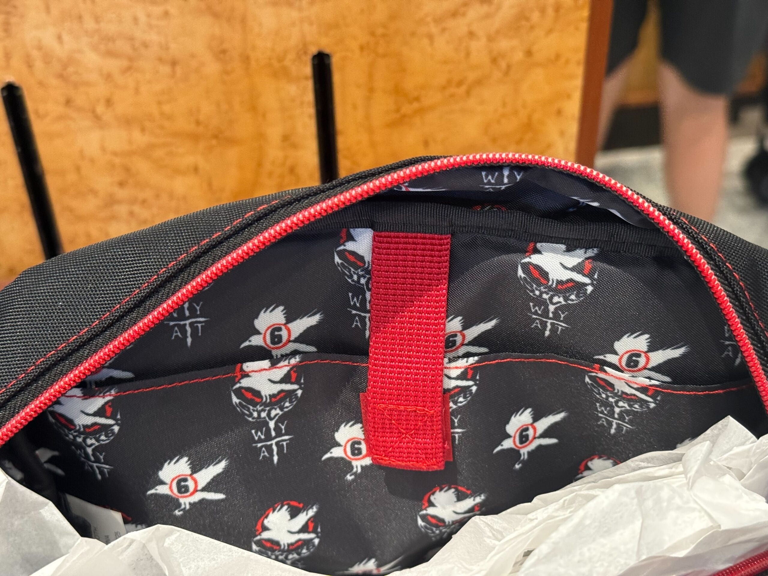 Open backpack showing black lining with a repeating HHN Merch 2025 pattern inside.