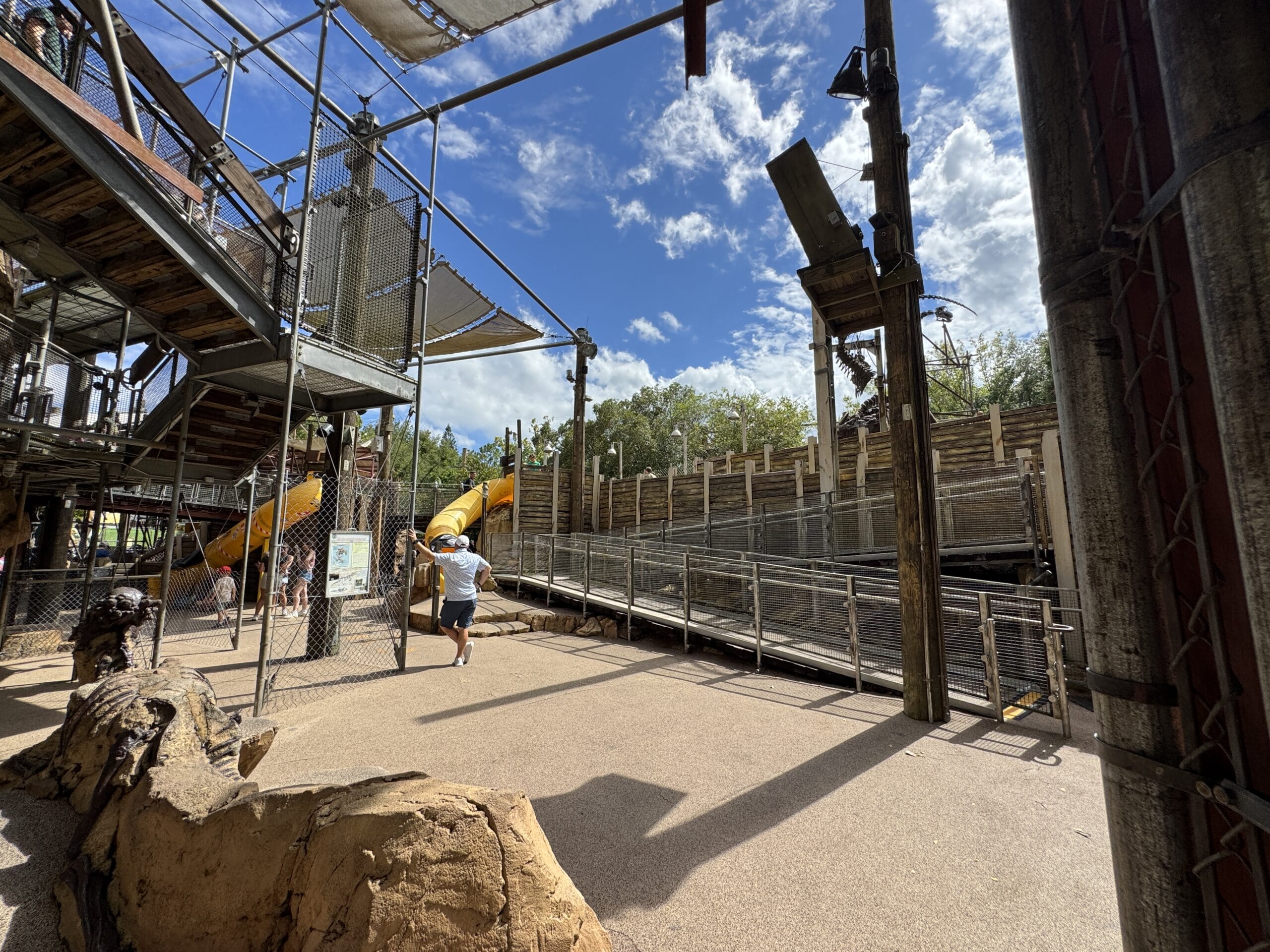 Outdoor playground at The Boneyard in Disney's Animal Kingdom, with metal structures, yellow slides, and blue skies.