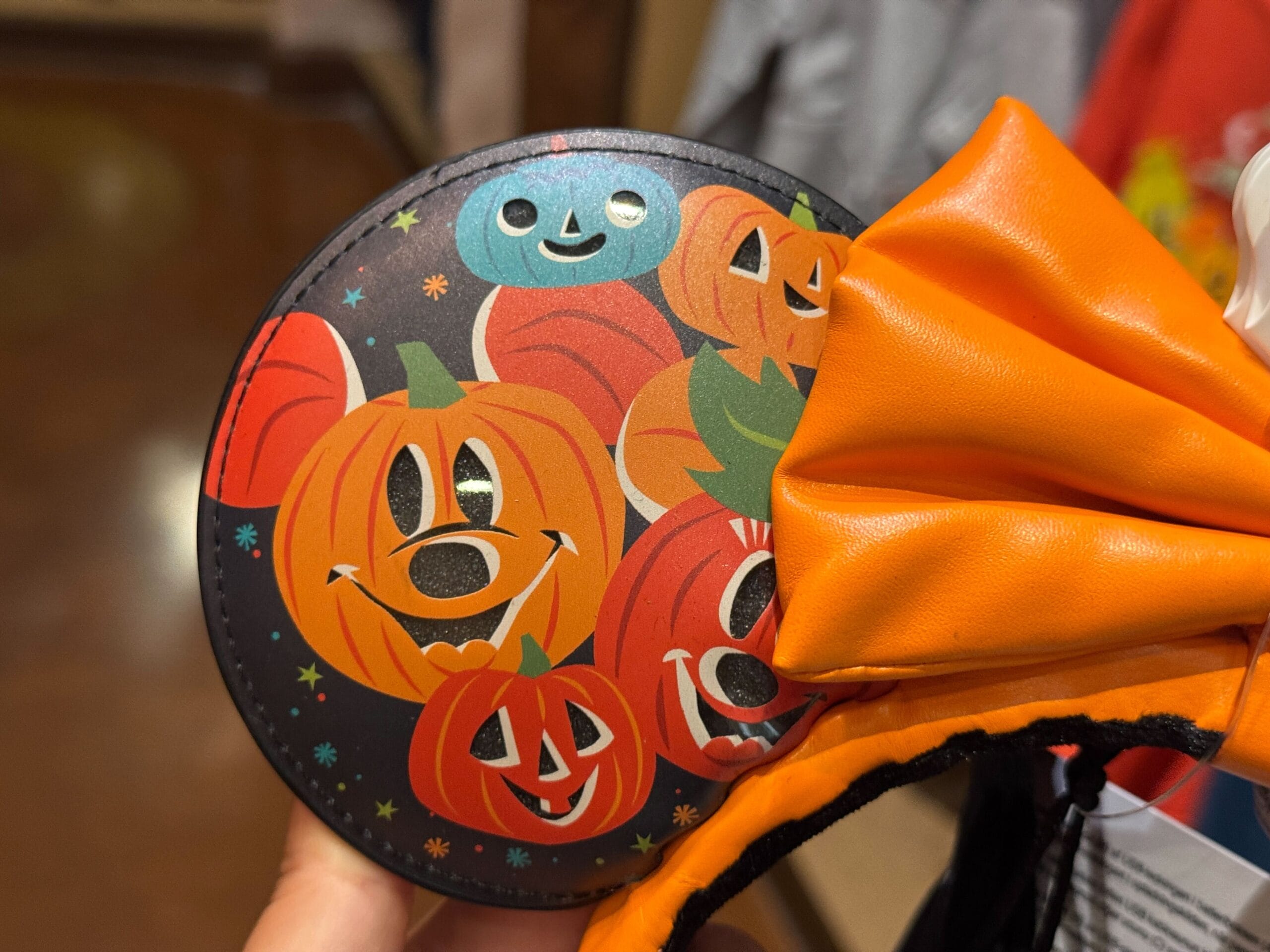 Close-up of Light-Up Halloween-themed Mickey Mouse ears with smiling jack-o'-lanterns and an orange bow.
