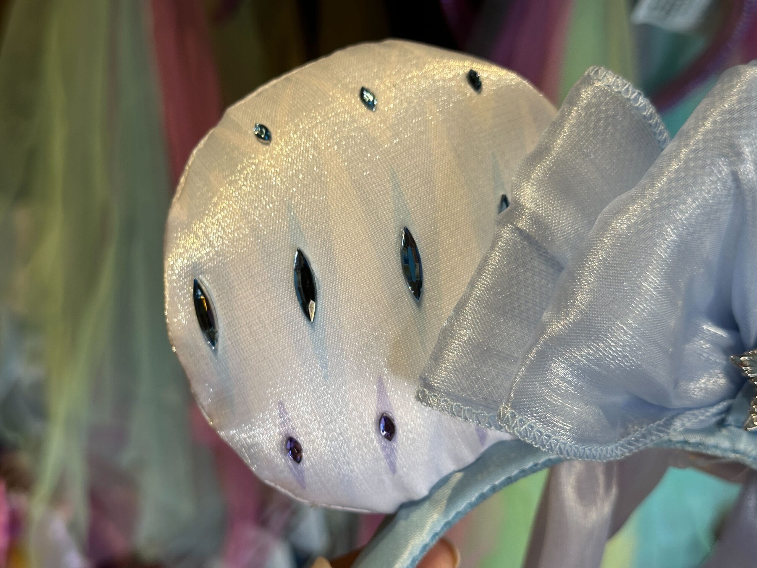 Close-up of a shimmery light blue Frozen 2 Elsa Ear Headband with sequins and a large sheer bow.