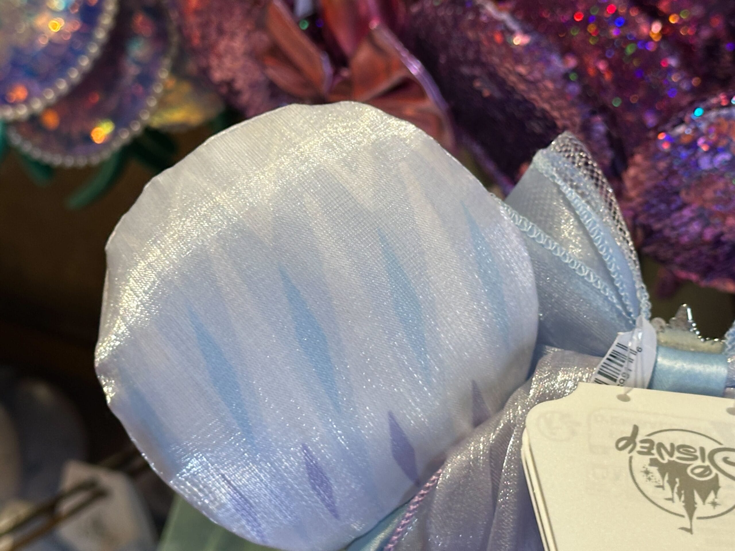 Close-up of a shimmery, light blue and white Frozen 2 Elsa Headband with a Disney tag attached.