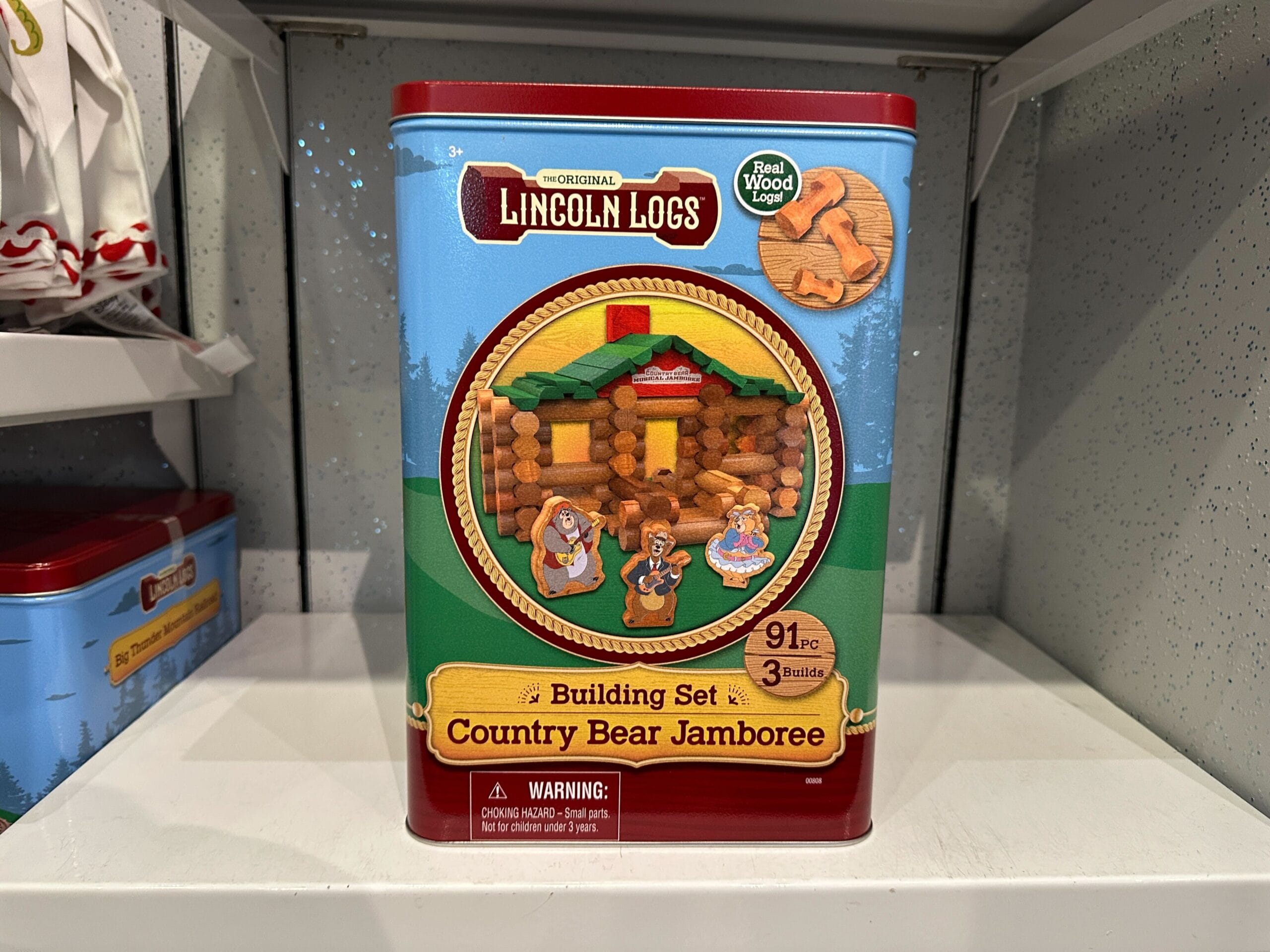 A Lincoln Logs Country Bear Jamboree building set tin, showing a log cabin and bear figures on the front.