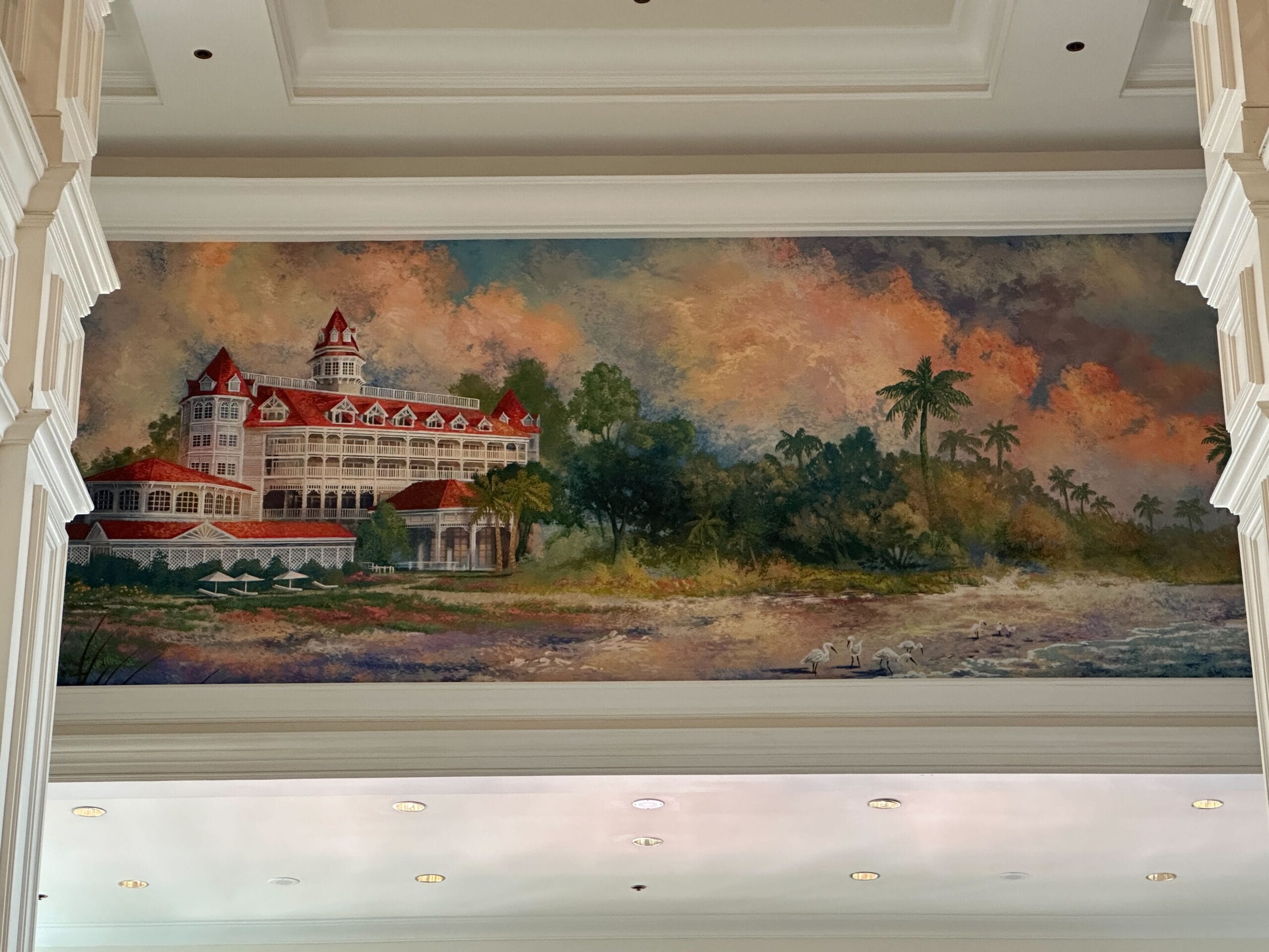 Mural of the Grand Floridian Resort by palm trees, beneath a colorful sky and sandy shoreline.