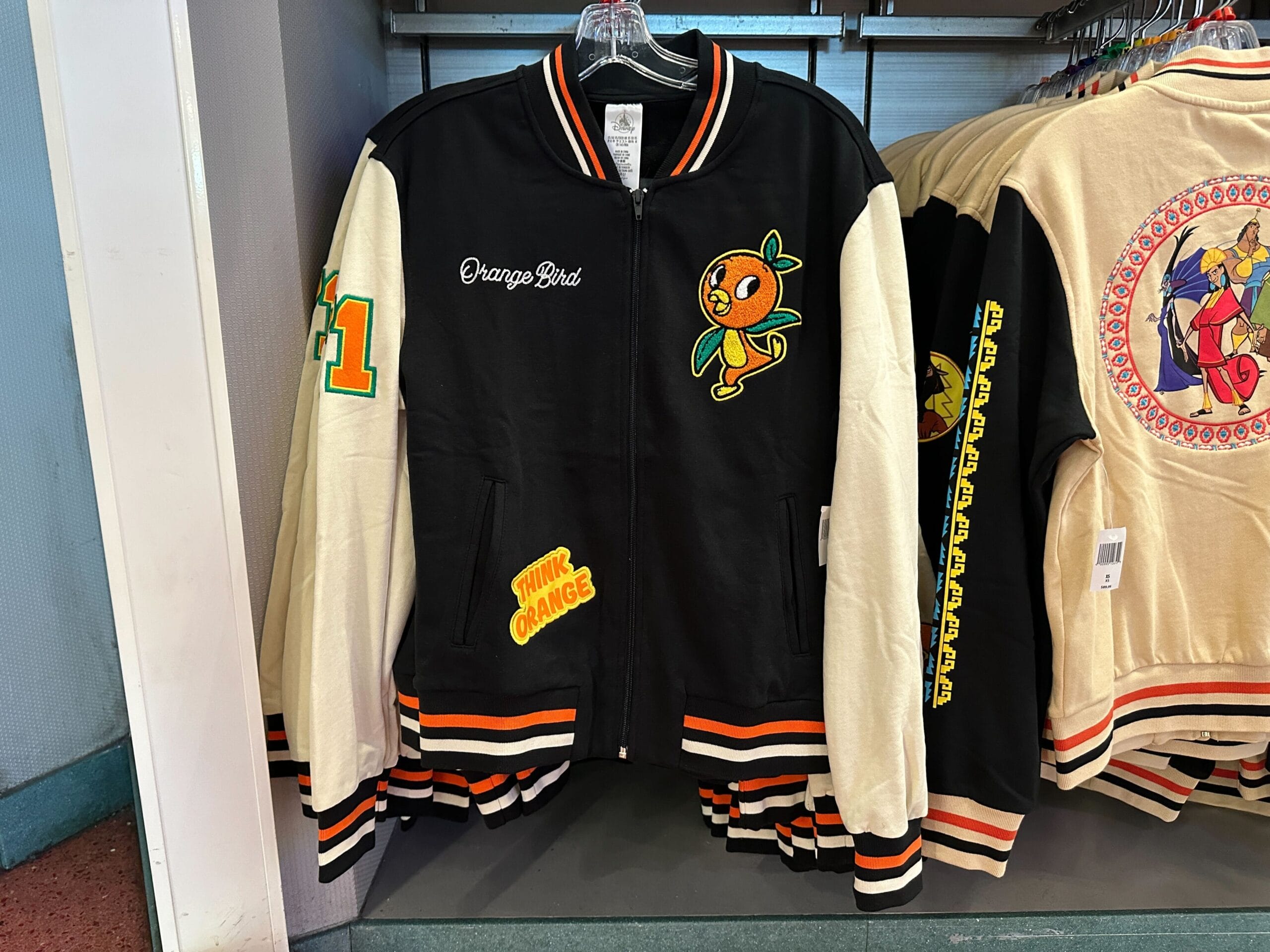 A black and cream Disney Letterman Jacket with an orange bird mascot and the text “Think Orange” on the front.