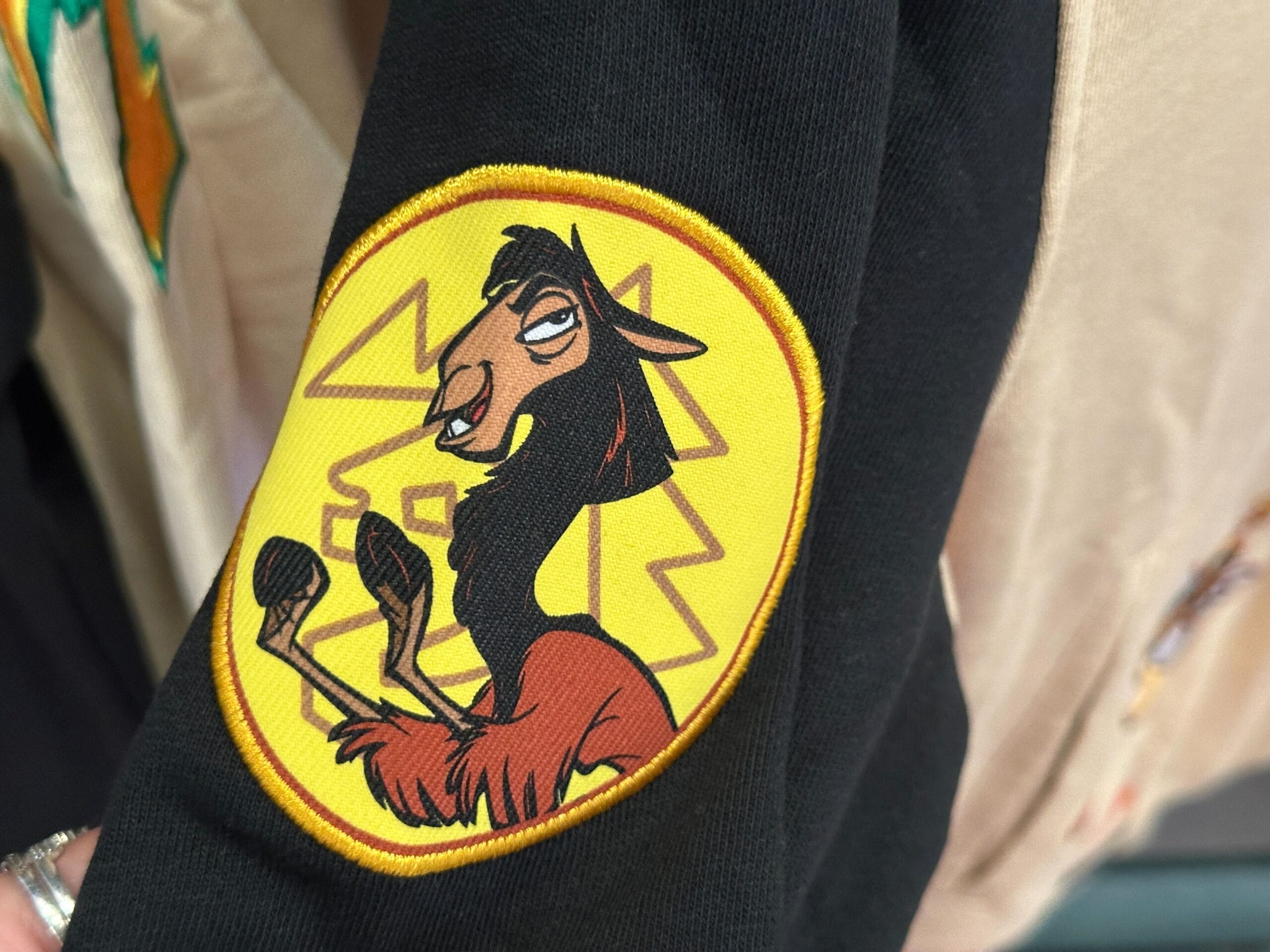 A patch of Kuzco the llama from "The Emperor’s New Groove" is sewn onto a black Disney Letterman Jacket sleeve.