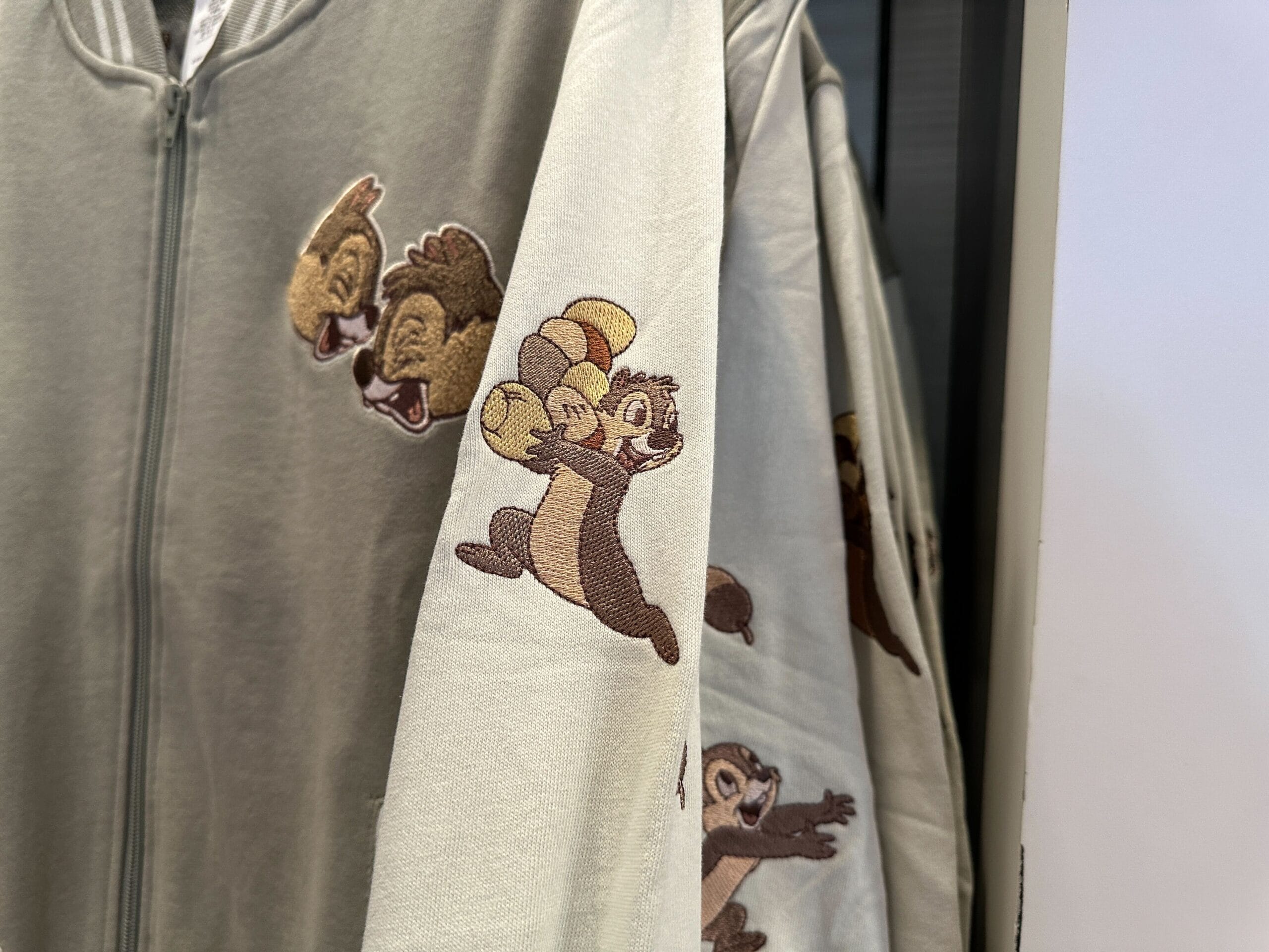A Disney letterman jacket with embroidered cartoon chipmunks; one runs while balancing nuts on its head.