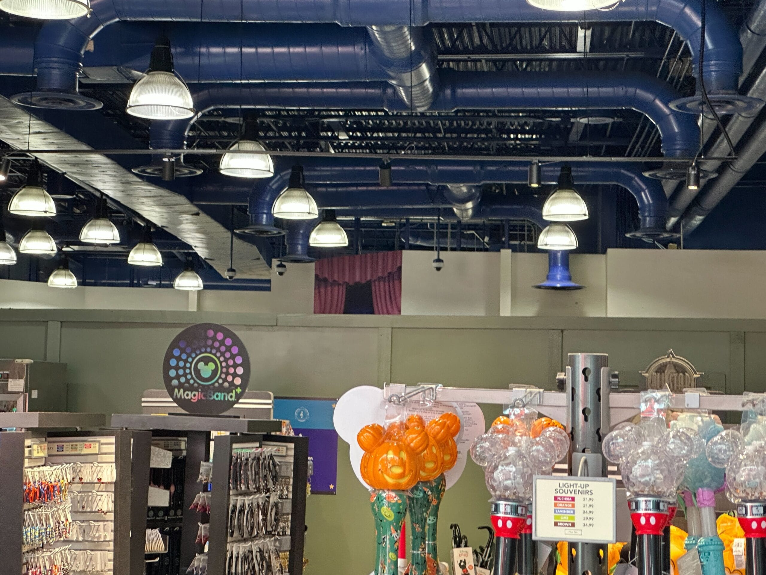 Retail store interior with shelves of colorful toys and accessories, blue ceiling pipes, and purple curtains in the background.