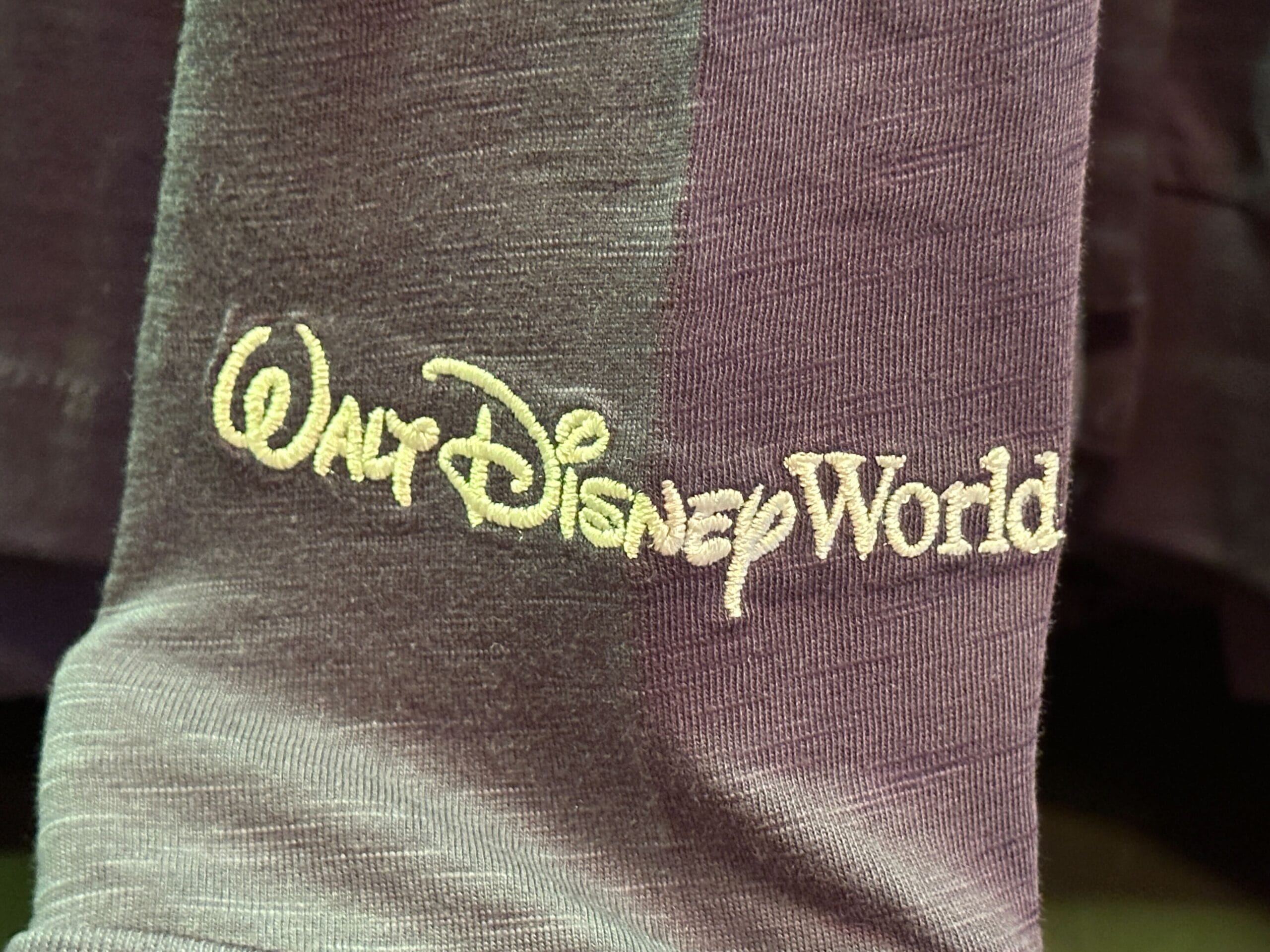 Close-up of purple fabric with "Walt Disney World" embroidered in yellow thread.