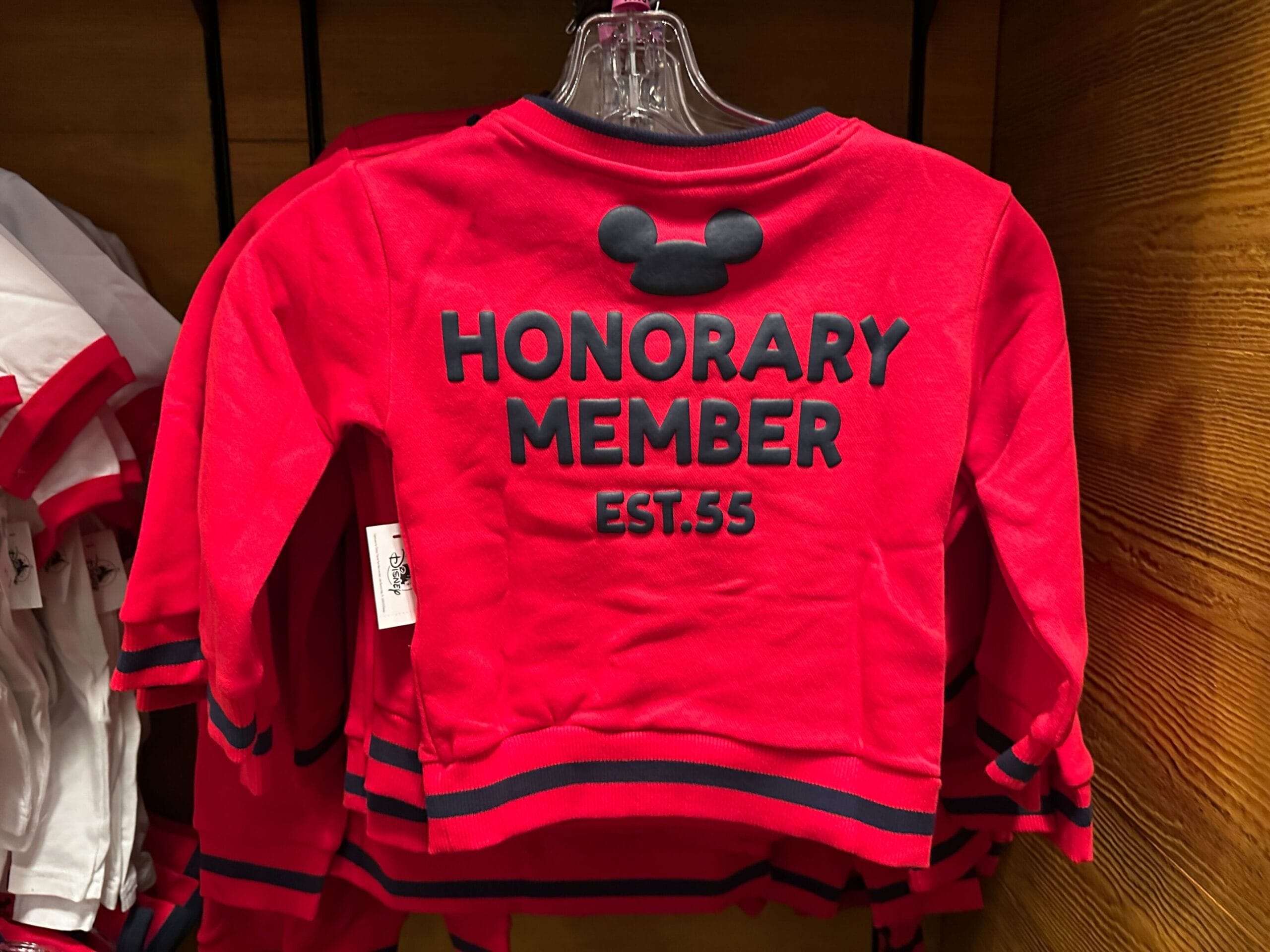 Red children's sweatshirt with Mickey Mouse ears and the words "HONORARY MEMBER EST. 55" printed on the back.