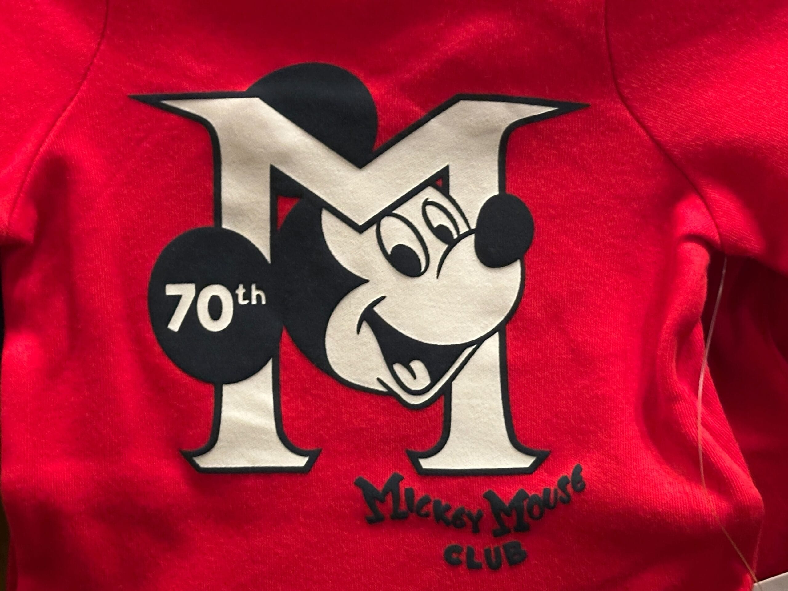 Red shirt with a large “M”, Mickey Mouse’s face, “70th” in a black circle, and “Mickey Mouse Club” text underneath.