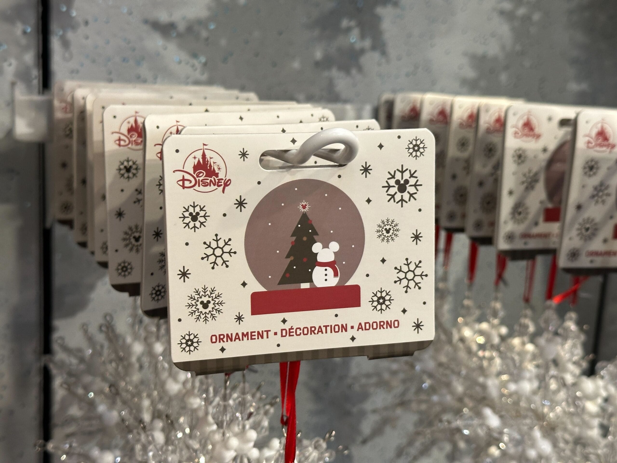 Disney holiday ornament tags featuring a Mickey Mouse silhouette, snowflakes, and a Christmas tree on display.