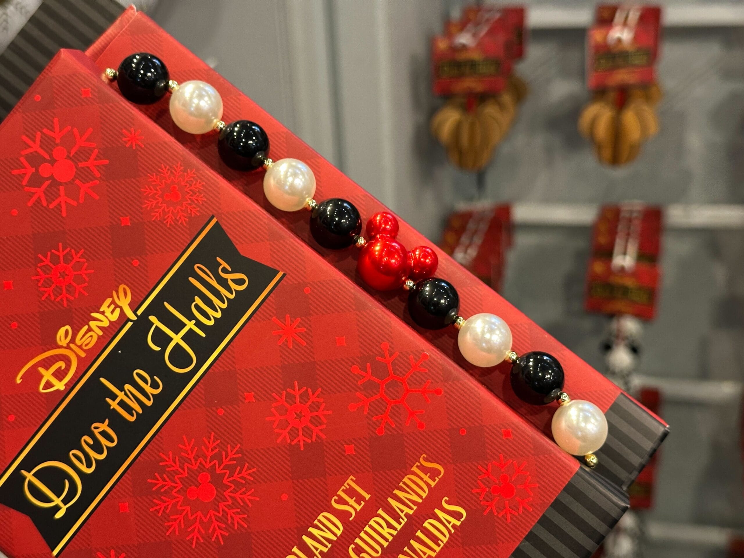 Disney "Deco the Halls" bead garland, with red, black, and white beads, on display near holiday ornaments.
