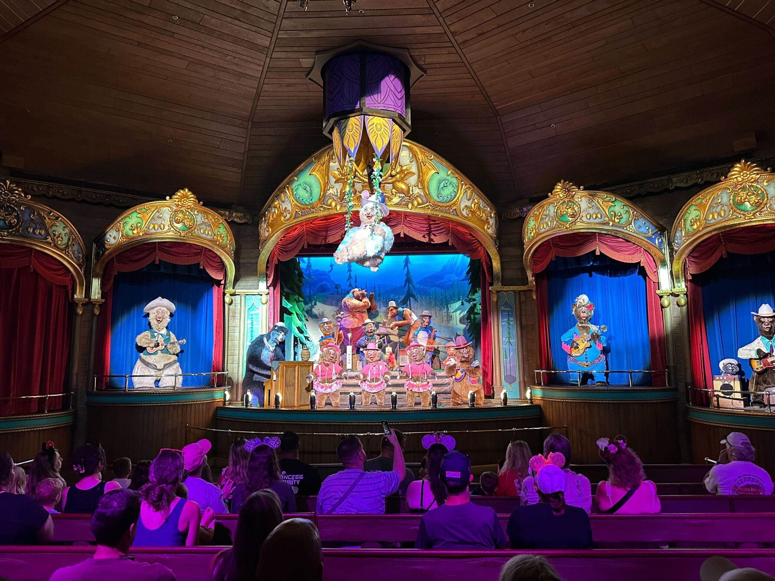 Animatronic bears perform on a decorated stage in the Country Bear Musical Jamboree, adorned with ornate gold accents.