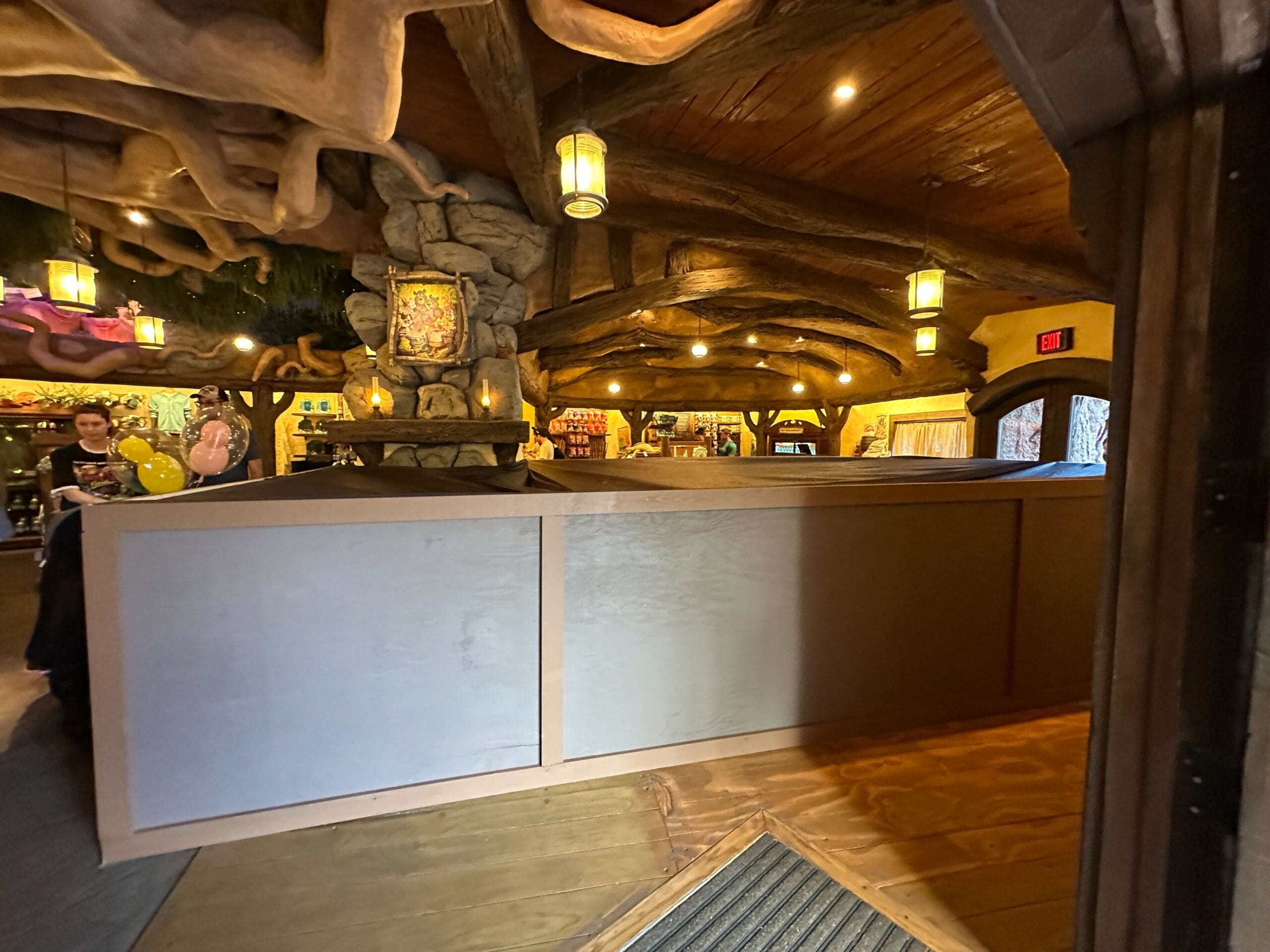 A themed restaurant interior with wooden beams and stone accents, featuring a large white partition blocking part of the area.