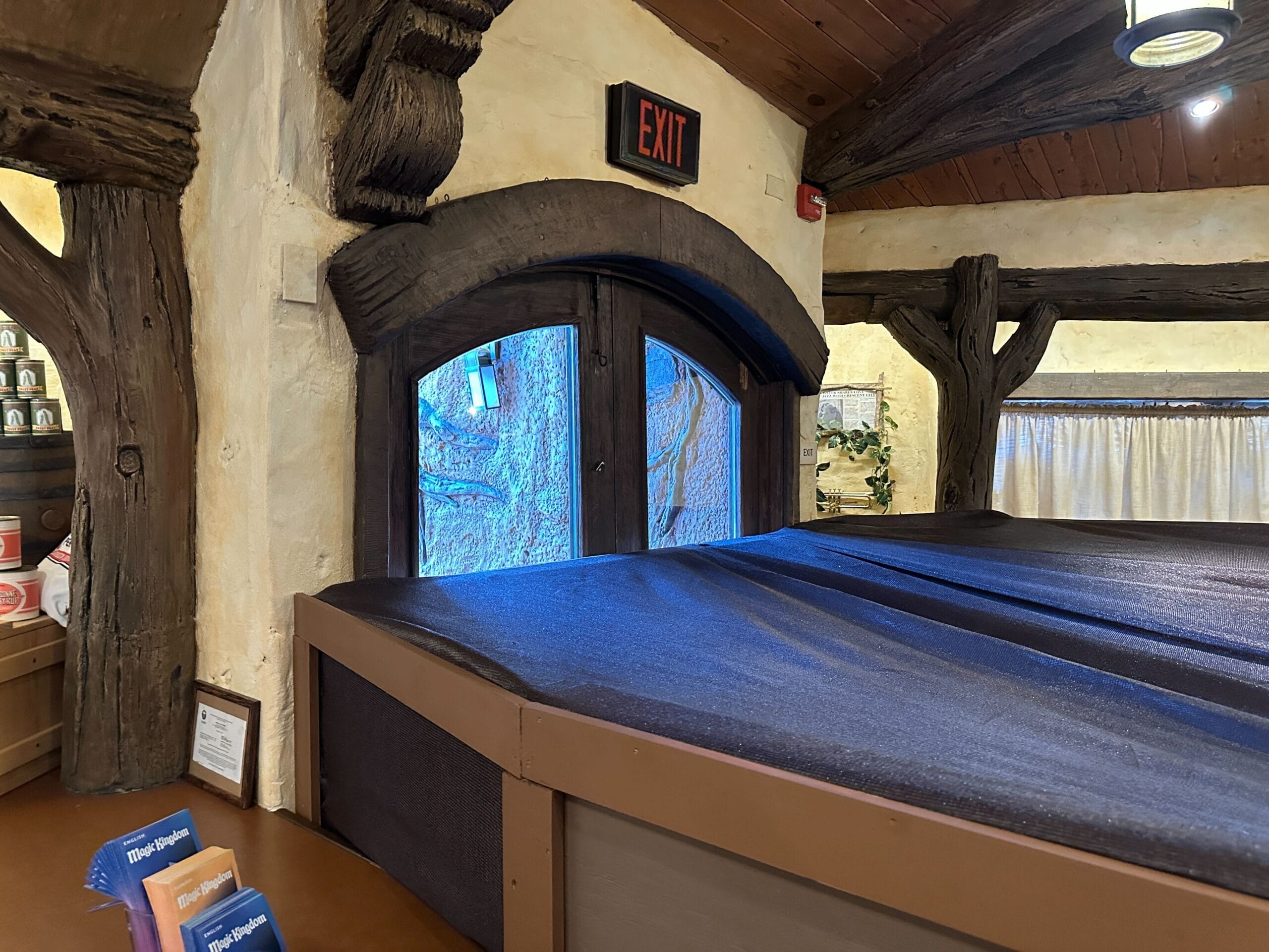 Arched wooden exit door with red EXIT sign, near rustic beams and Critter Co-Op construction walls inside a building.