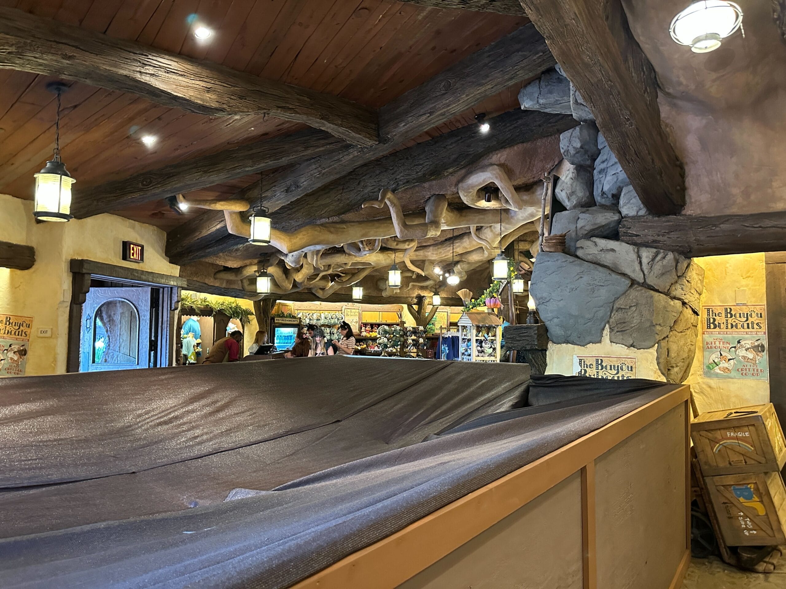 Rustic restaurant interior with wooden beams, draped cloth, and Construction Walls near the entrance in the background.