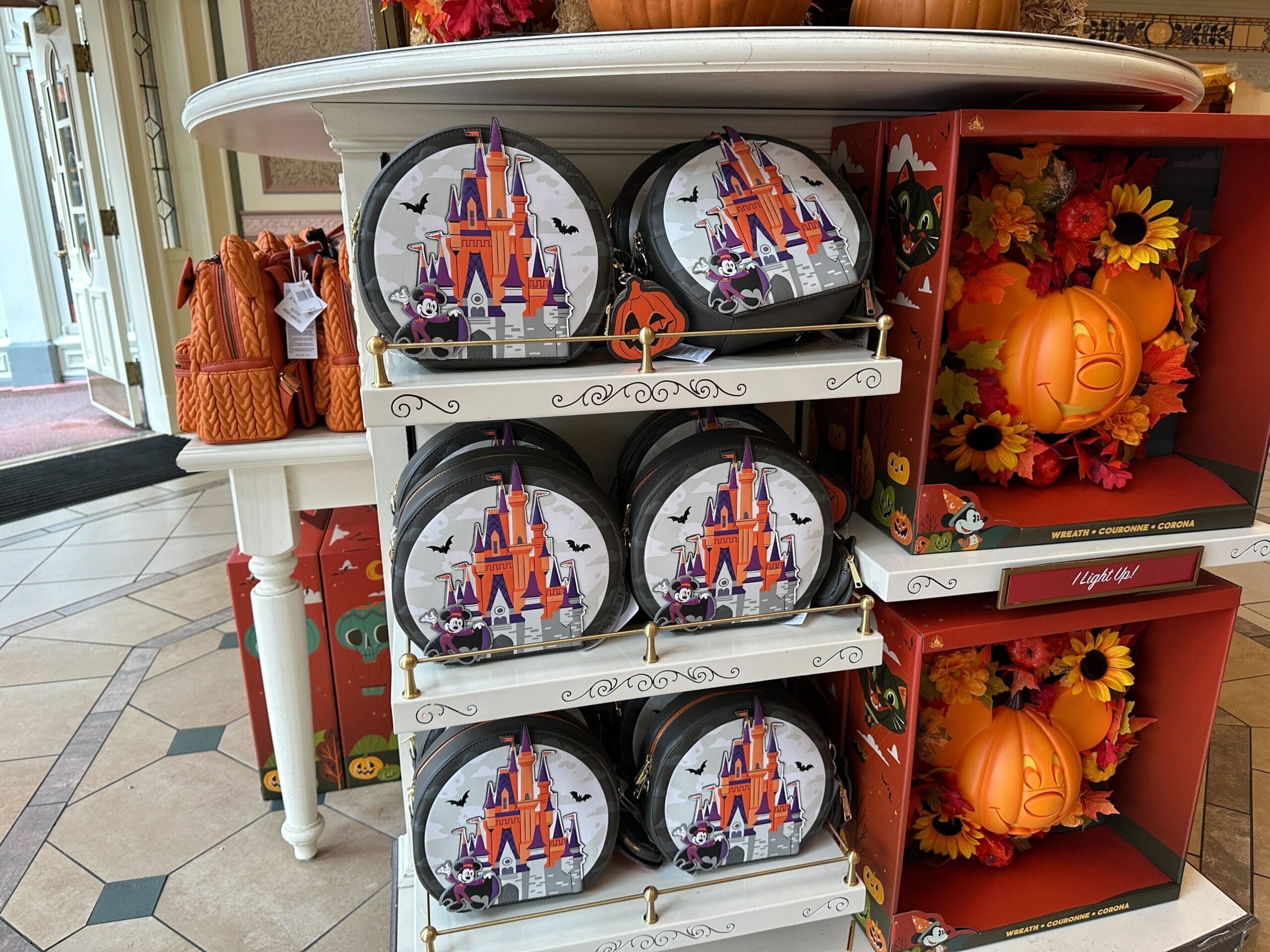 Round tins with a Halloween-themed castle design, perfect as Magic Kingdom or Halloween merchandise among pumpkin decor.