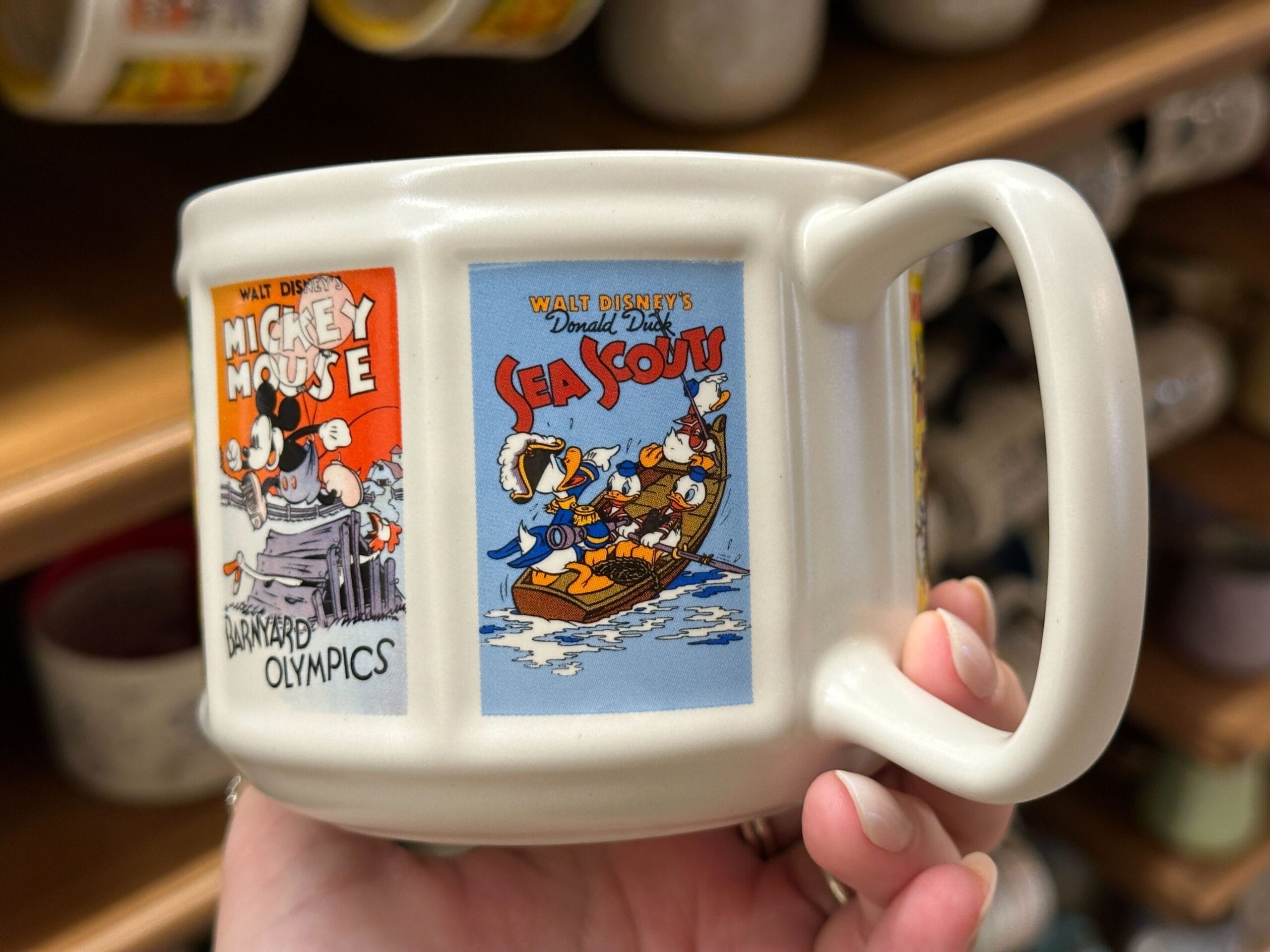 White mug featuring vintage Mickey, Minnie, and Donald Duck cartoon artwork, including "Barnyard Olympics" and "Sea Scouts.
