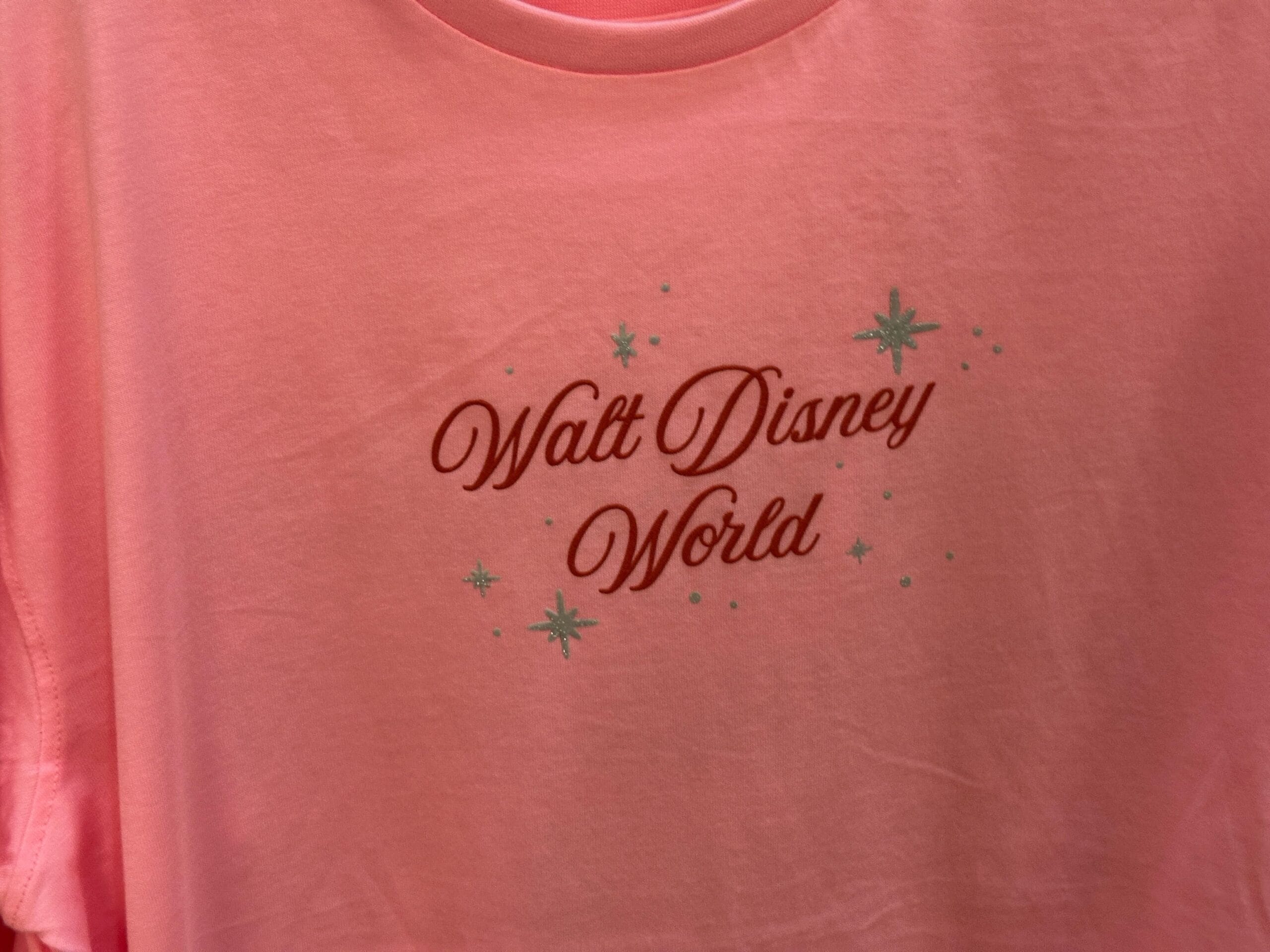 Pink T-shirt with "Walt Disney World" written in red script and small blue star accents around the text.