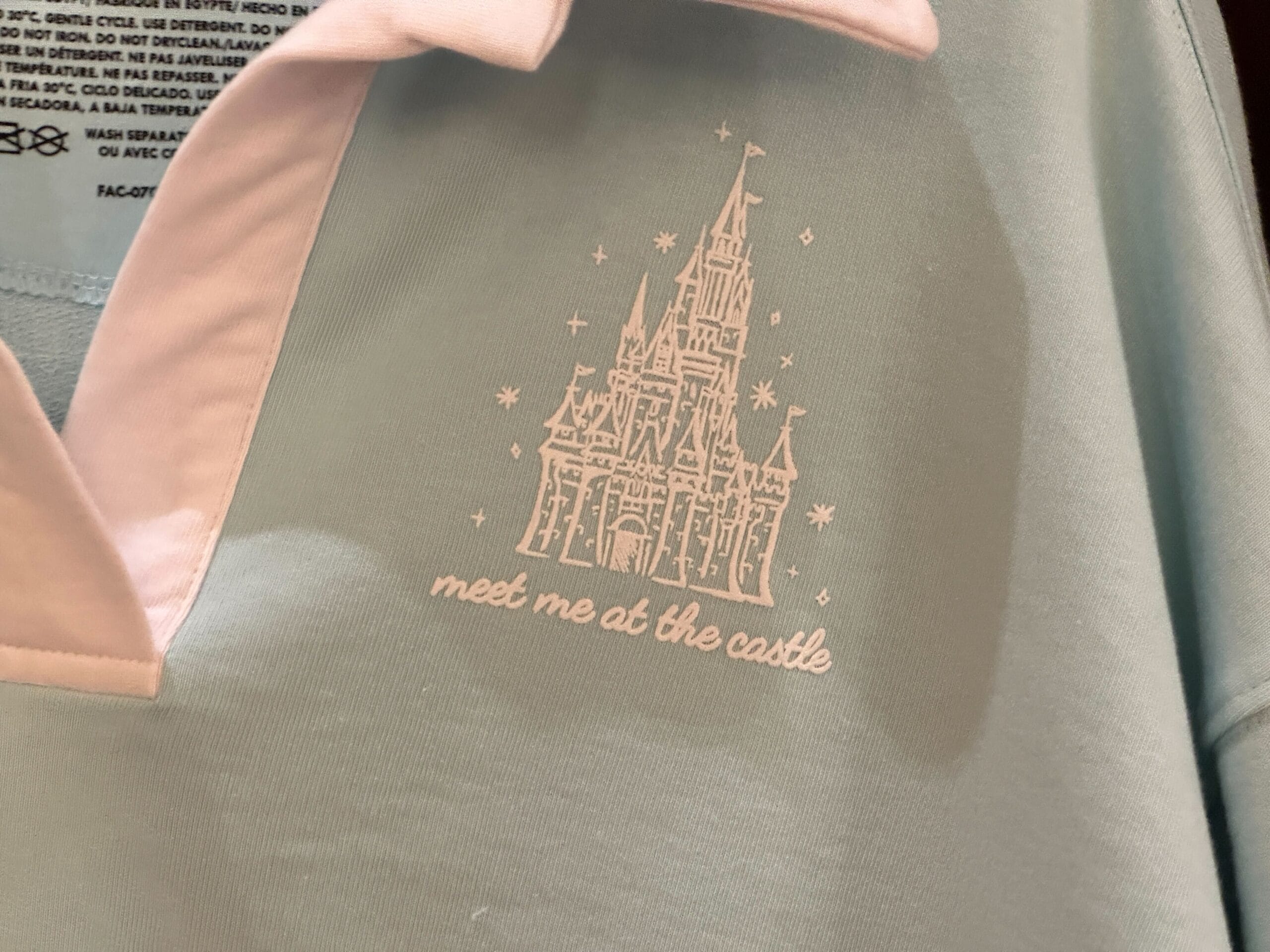 Light blue and pink shirt with a white castle graphic and text that reads "meet me at the castle.