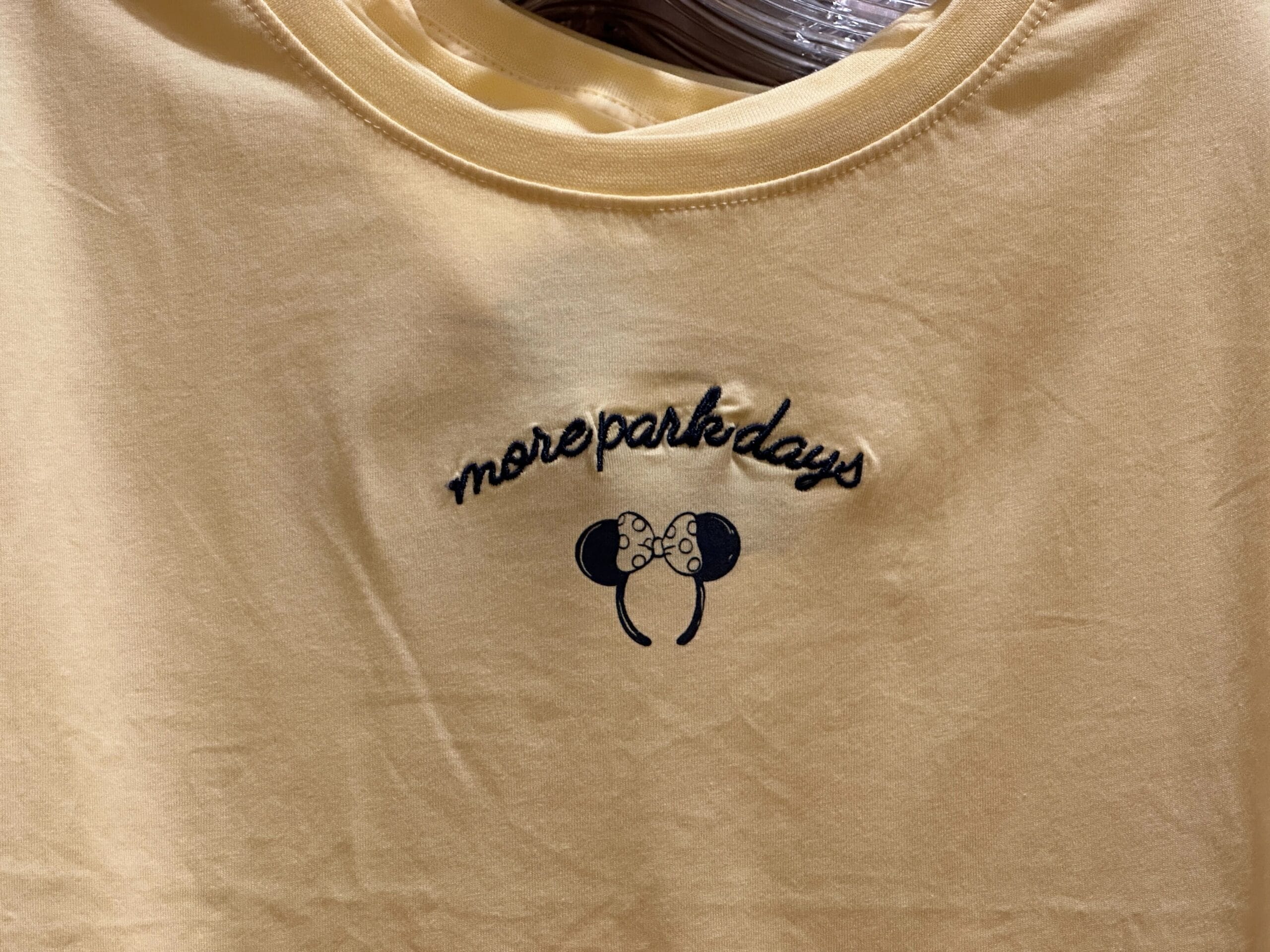Yellow shirt with "more park days" text and a drawing of mouse ears with a bow on the front.